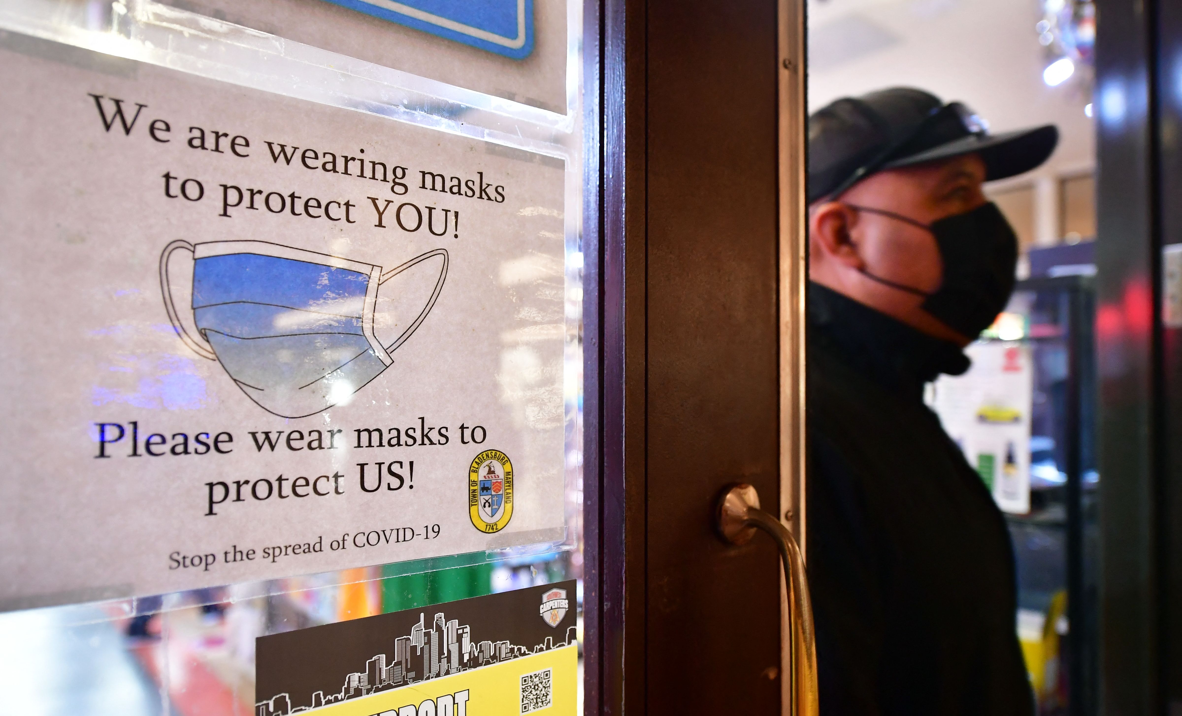 A man wears his mask as he walks past a sign posted on a storefront reminding people to wear masks, on Feb. 25, 2022 in Los Angeles. (FREDERIC J. BROWN/AFP via Getty Images)