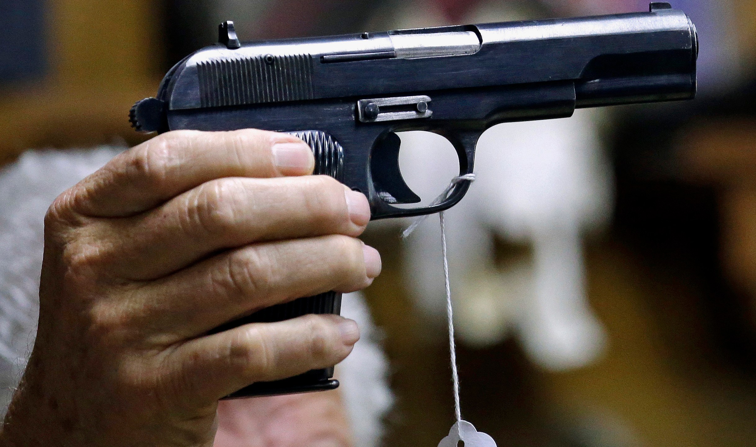 A sales clerk holds a pistol during an auction in Rochester, Wash., on Oct. 20, 2017. (AP Photo/Elaine Thompson, File)