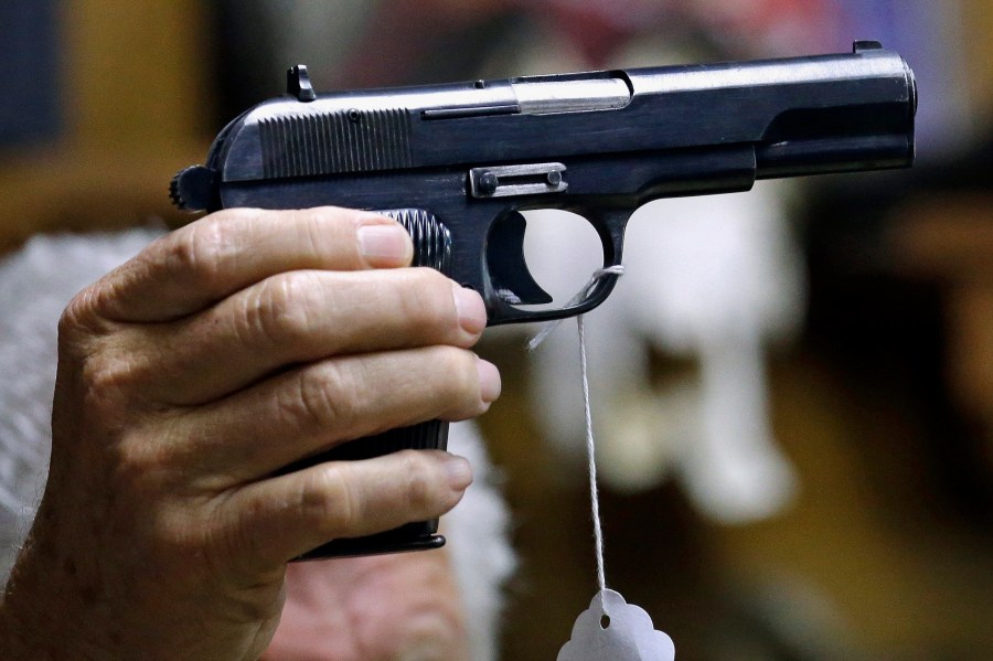 A sales clerk holds a pistol during an auction in Rochester, Wash., on Oct. 20, 2017. (AP Photo/Elaine Thompson, File)