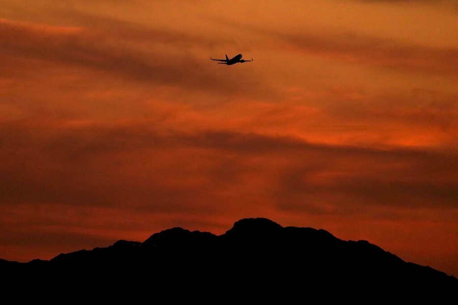 A passenger jet is silhouetted against the sky at dusk as it takes off from Sky Harbor Airport, Saturday, April 2, 2022, in Phoenix. (AP Photo/Charlie Riedel)