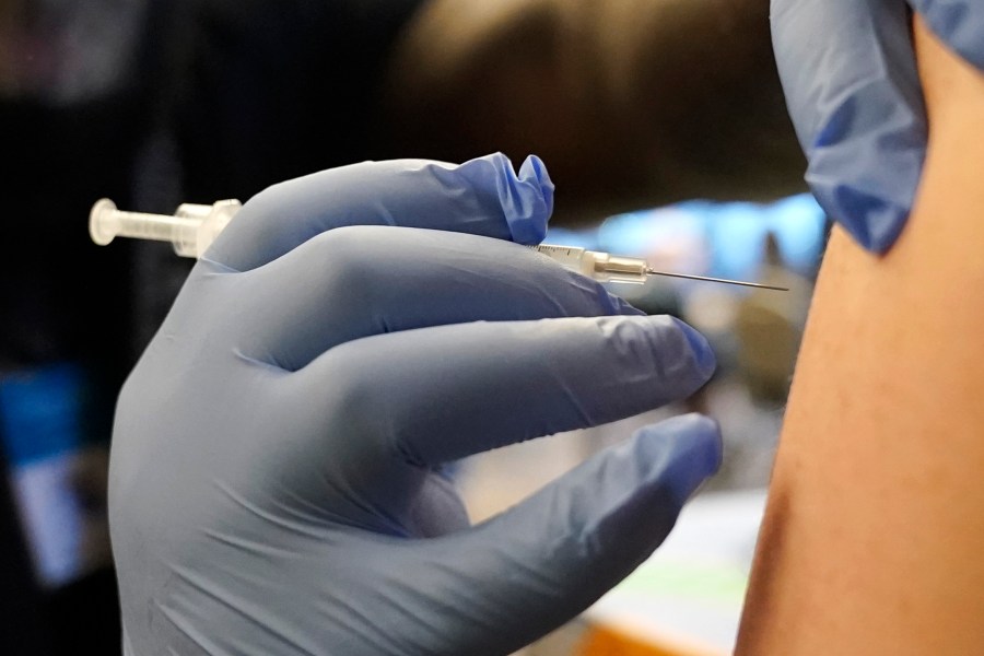 DeMarcus Hicks, a recent graduate of nursing school who is working as a contractor with the Federal Emergency Management Agency, gives a person a Pfizer COVID-19 vaccine booster shot, on Dec. 20, 2021 in Federal Way, Wash. (Ted S. Warren/Associated Press)