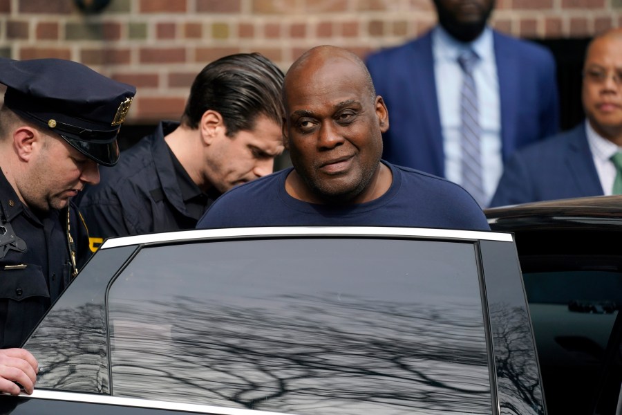 Law enforcement officials lead subway shooting suspect Frank R. James, 62, center right, away from a police station and into a vehicle, in New York on April 13, 2022. (John Minchillo/Associated Press)