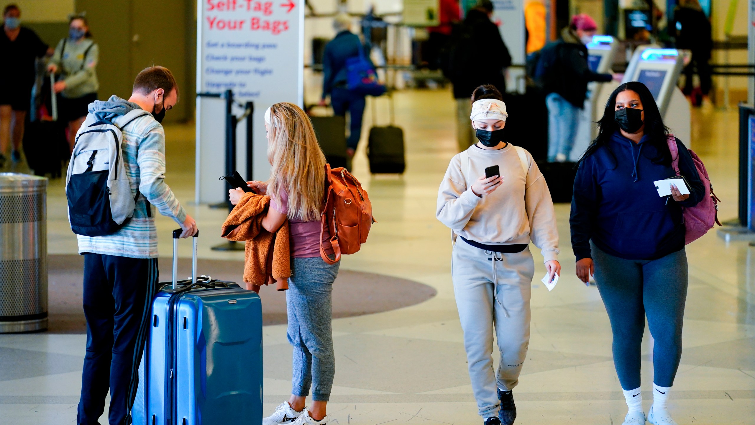 Travelers wearing protective masks as a precaution against the spread of the coronavirus move about the a terminal at the Philadelphia International Airport on April 19, 2022. (Matt Rourke/Associated Press)