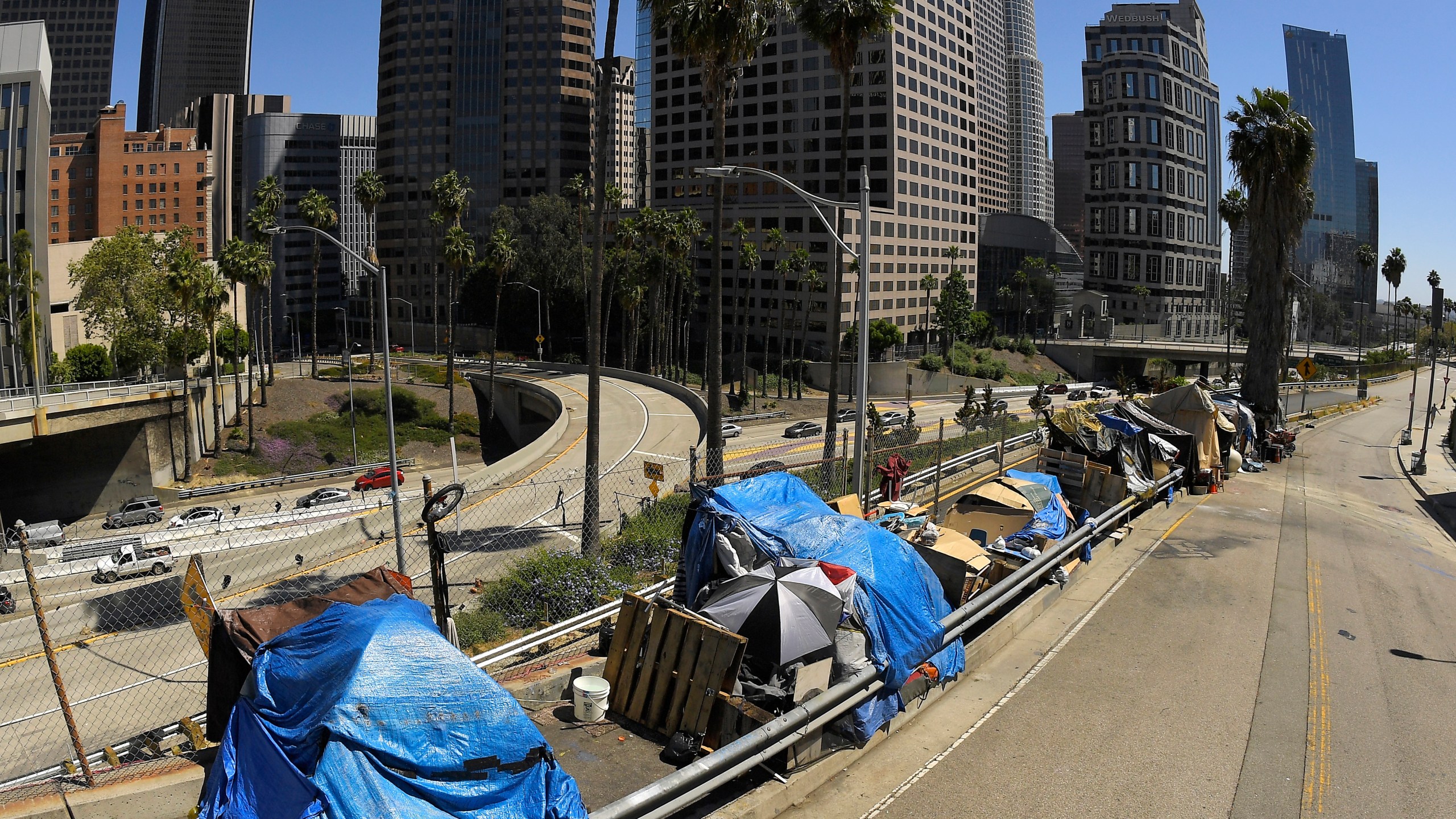 This May 21, 2020, file photo shows a homeless encampment on Beaudry Avenue as traffic moves along Interstate 110 below during the coronavirus outbreak, in downtown Los Angeles. (AP Photo/Mark J. Terrill,File)