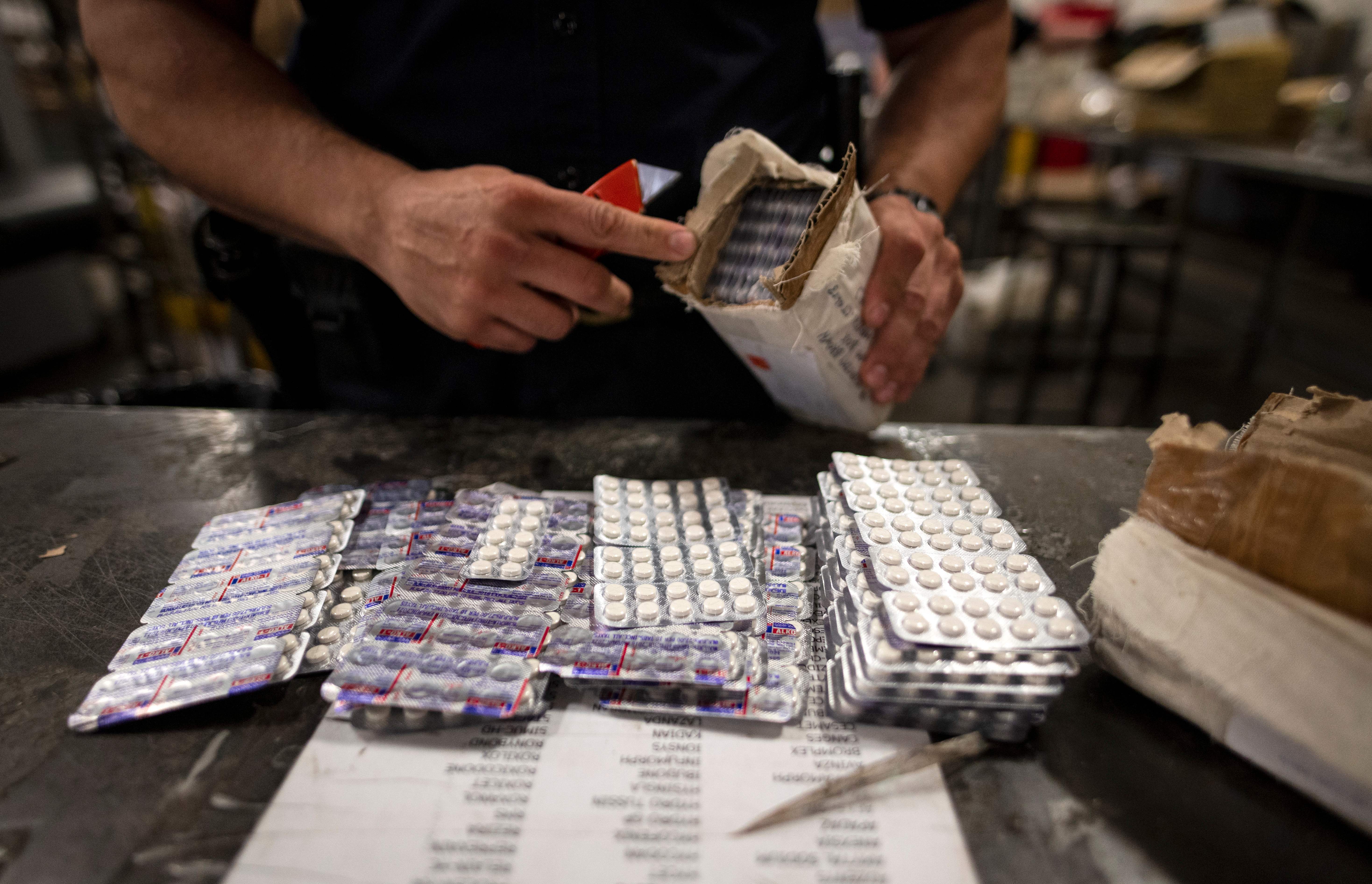 An officer from the US Customs and Border Protection, Trade and Cargo Division finds Oxycodon pills in a parcel at John F. Kennedy Airport's US Postal Service facility on June 24, 2019 in New York. In a windowless hangar at New York's JFK airport, dozens of law enforcement officers sift through packages, looking for fentanyl, a drug that is killing Americans every day. (Johannes Eisele/AFP via Getty Images)