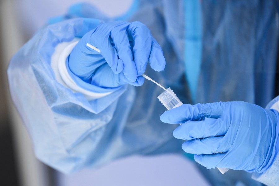 This file photo shows a health care worker placing a test swab into solution for a PCR COVID-19 test in California on Jan. 18, 2022. (PATRICK T. FALLON/AFP via Getty Images)