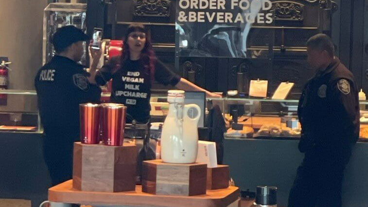 This image released by PETA shows police near an activist (center) who glued her hand to a café counter in protest of the chain's policies regarding plant-based milk. (PETA)