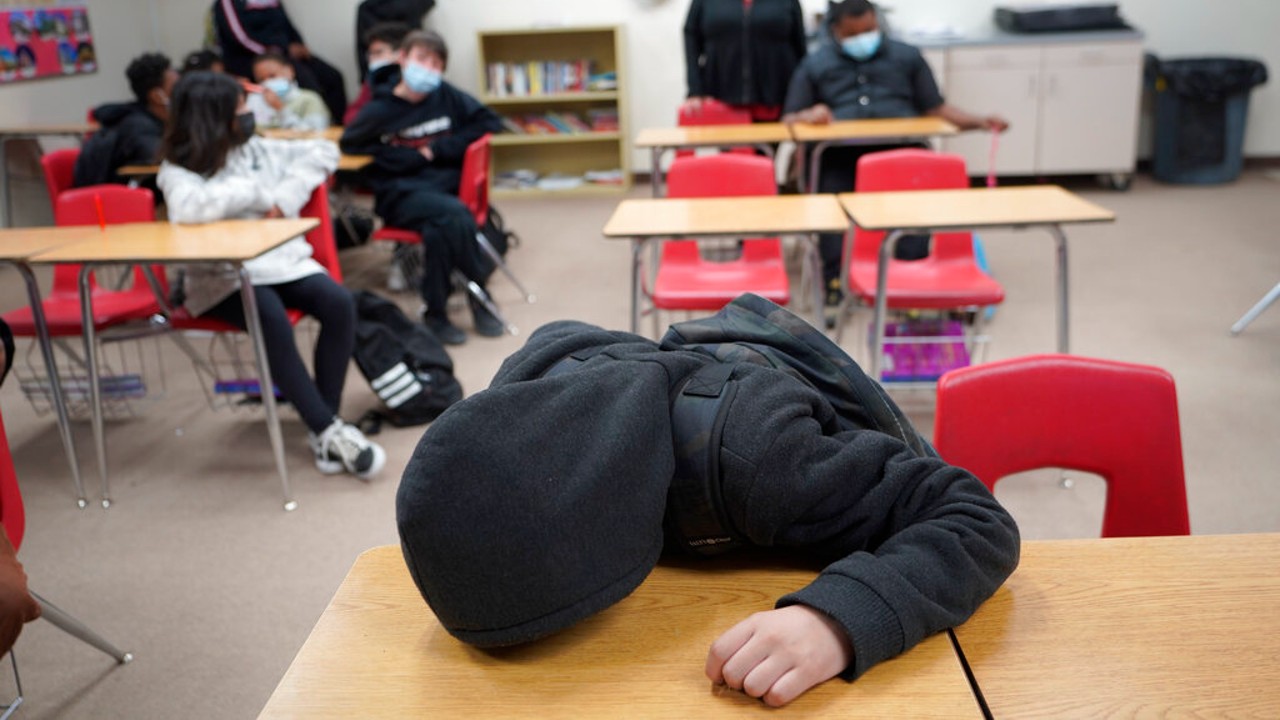 An unidentified student rests on his desk as the Mojave Unified School District Superintendent Katherine Aguirre, center rear, addresses students in California City, on Friday, March 11, 2022. (AP Photo/Damian Dovarganes)