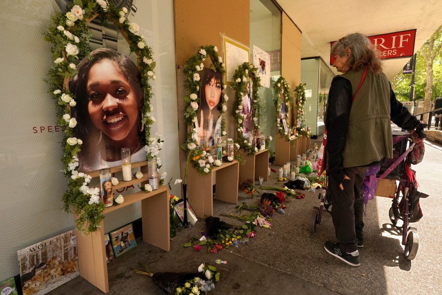 A passerby pauses at a memorial for the people killed in mass shooting in Sacramento, Calif., April 6, 2022. Prosecutors have filed murder charges in a mass shooting that rocked California’s capital city a month ago. District Attorney Anne Marie Schubert said Tuesday, May 3, that three men have been charged with murder in the slayings. (AP Photo/Rich Pedroncelli, File)