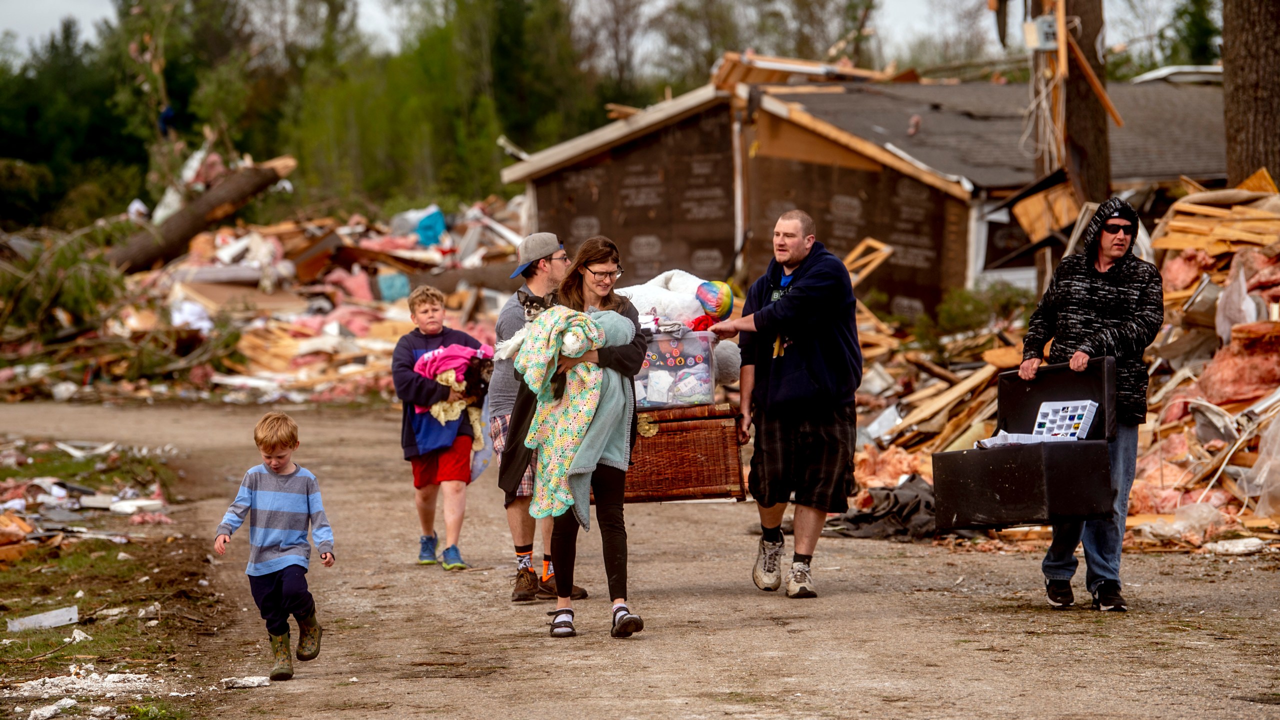 Resident Stephanie Kerwin, center, holds her baby Octavius in one arm and dog Pixie in the other as she and her family carry what they could salvage from her home in Nottingham Forest Mobile Home Park, Saturday, May 21, 2022, in Gaylord, Mich., following a tornado the day before. "This morning is when it first hit me...I could have lost people that I really love. I am so grateful," Kerwin said. (Jake May/MLive.com/The Flint Journal via AP)