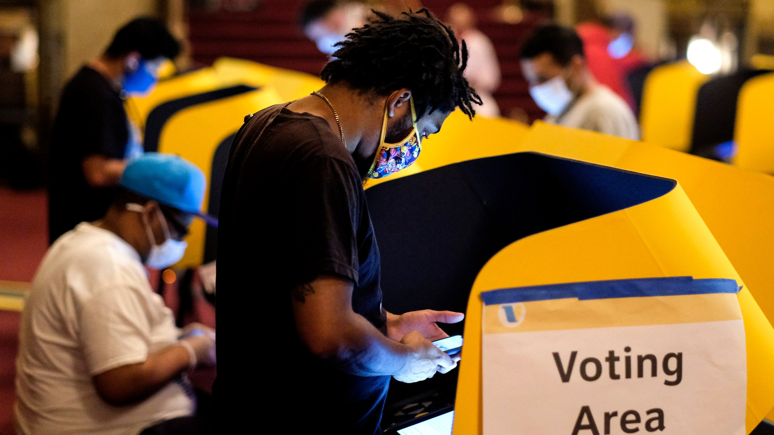 A voter casts his ballot at a vote center in Pantages Theatre during the election day in Hollywood Tuesday, Nov. 3, 2020. (AP Photo/Ringo H.W. Chiu)