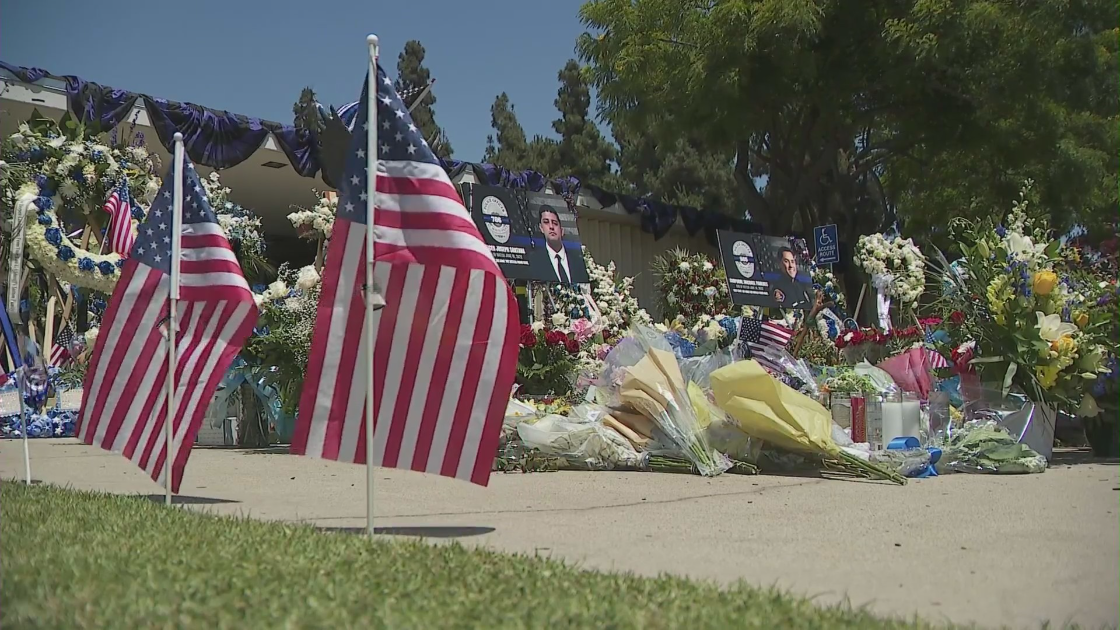 Photos of two El Monte police officers fatally shot in the line of duty adorn a growing memorial after the police station on June 17, 2022. (KTLA)