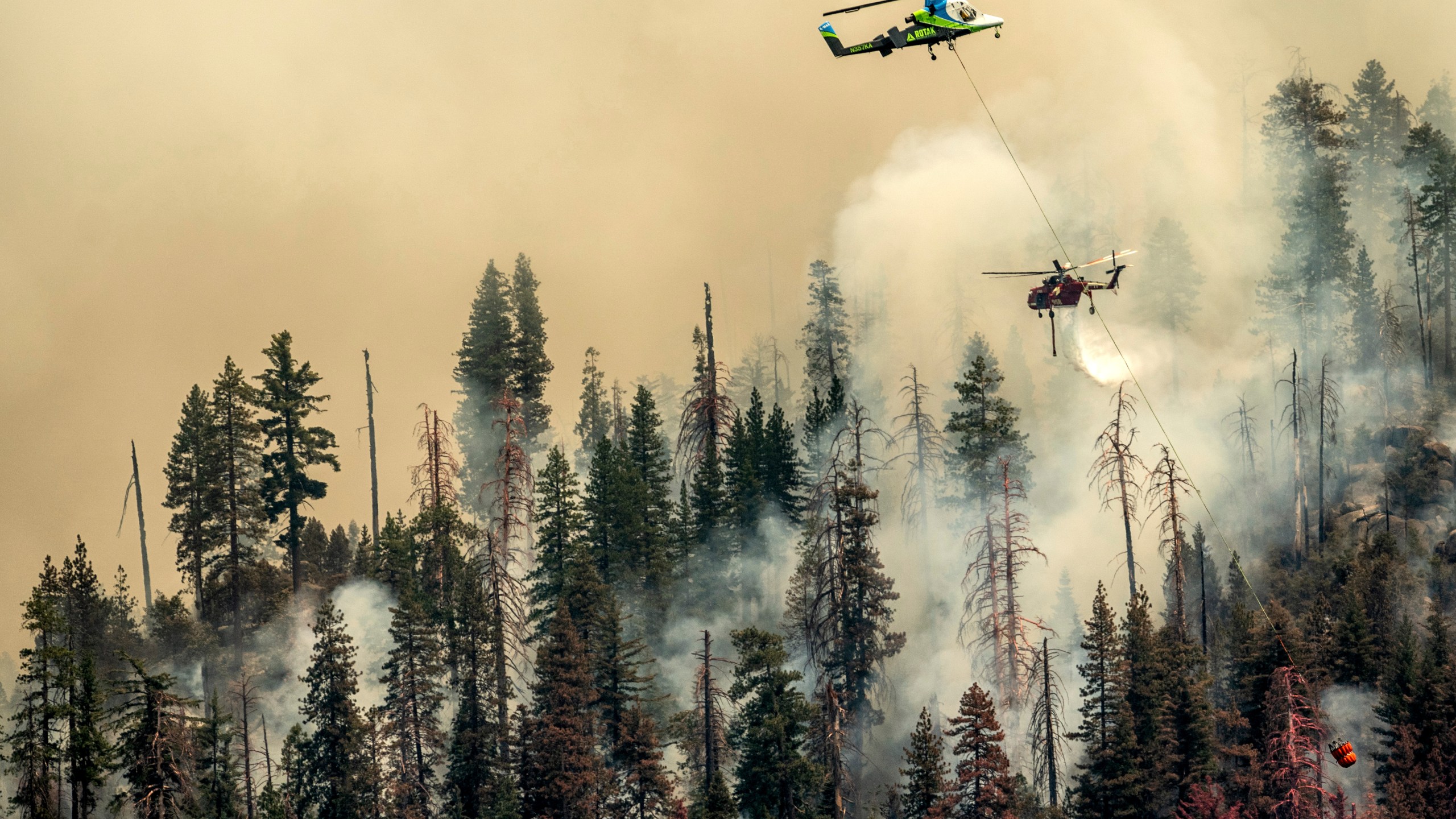 Seen from unincorporated Mariposa County, Calif., a helicopter drops water on the Washburn Fire burning in Yosemite National Park on July 9, 2022. (Noah Berger)