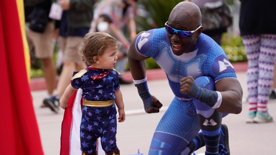 Jay Acey, right, dressed as A-Train from the television series "The Boys," mingles with Maddox Cruz, 1, of Orange, Calif., outside Preview Night at the 2022 Comic-Con International at the San Diego Convention Center, Wednesday, July 20, 2022, in San Diego. (AP Photo/Chris Pizzello)