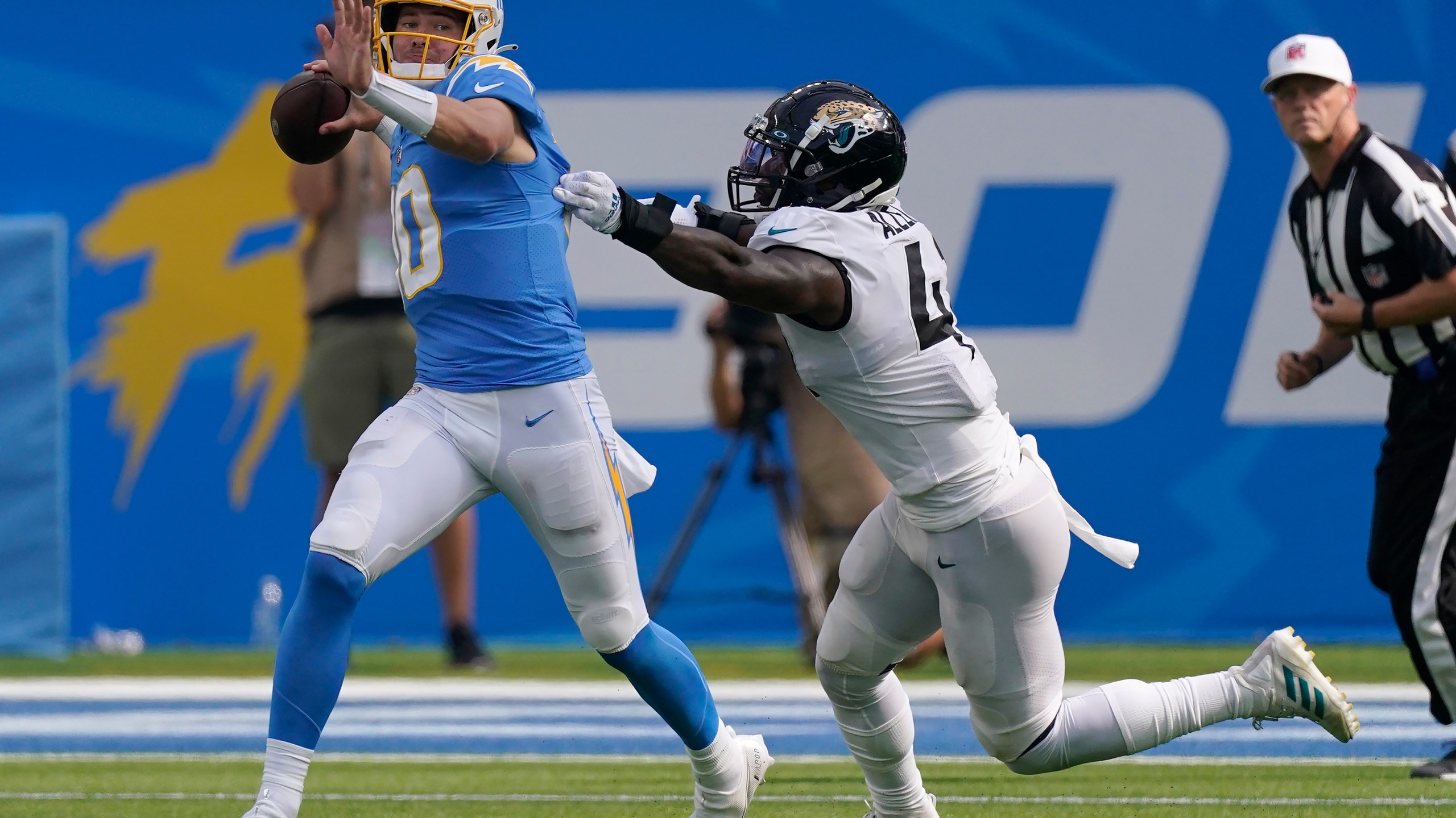 Los Angeles Chargers quarterback Justin Herbert, left, passes while pressured by Jacksonville Jaguars linebacker Josh Allen during the second half of an NFL football game in Inglewood, Calif., Sunday, Sept. 25, 2022. (AP Photo/Mark J. Terrill)