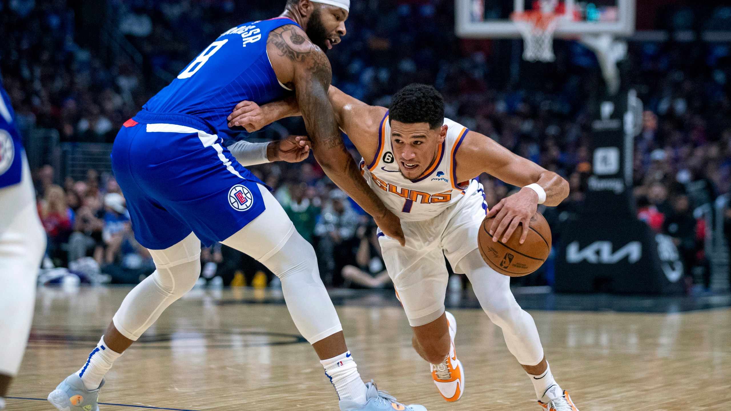 Phoenix Suns guard Devin Booker, right, drives past Los Angeles Clippers forward Marcus Morris Sr. during the first half of an NBA basketball game, Sunday, Oct. 23, 2022 in Los Angeles. (AP Photo/Alex Gallardo)