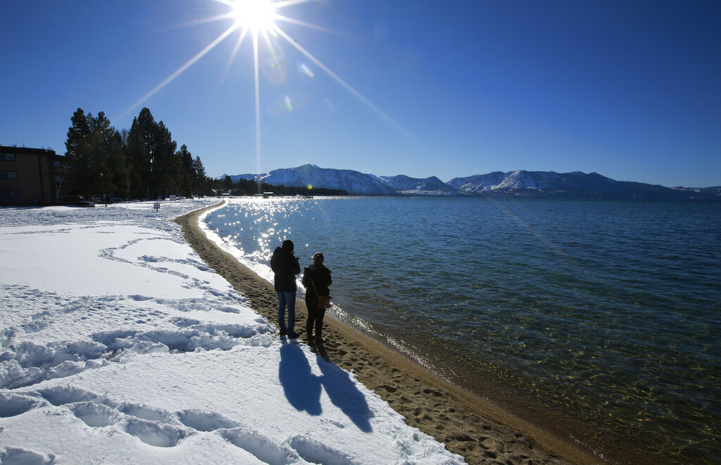 FILE - In this March 5, 2018, file photo, sunlight shimmers off the snow and waters of Lake Tahoe in South Lake Tahoe, Calif. (AP Photo/Rich Pedroncelli, File)