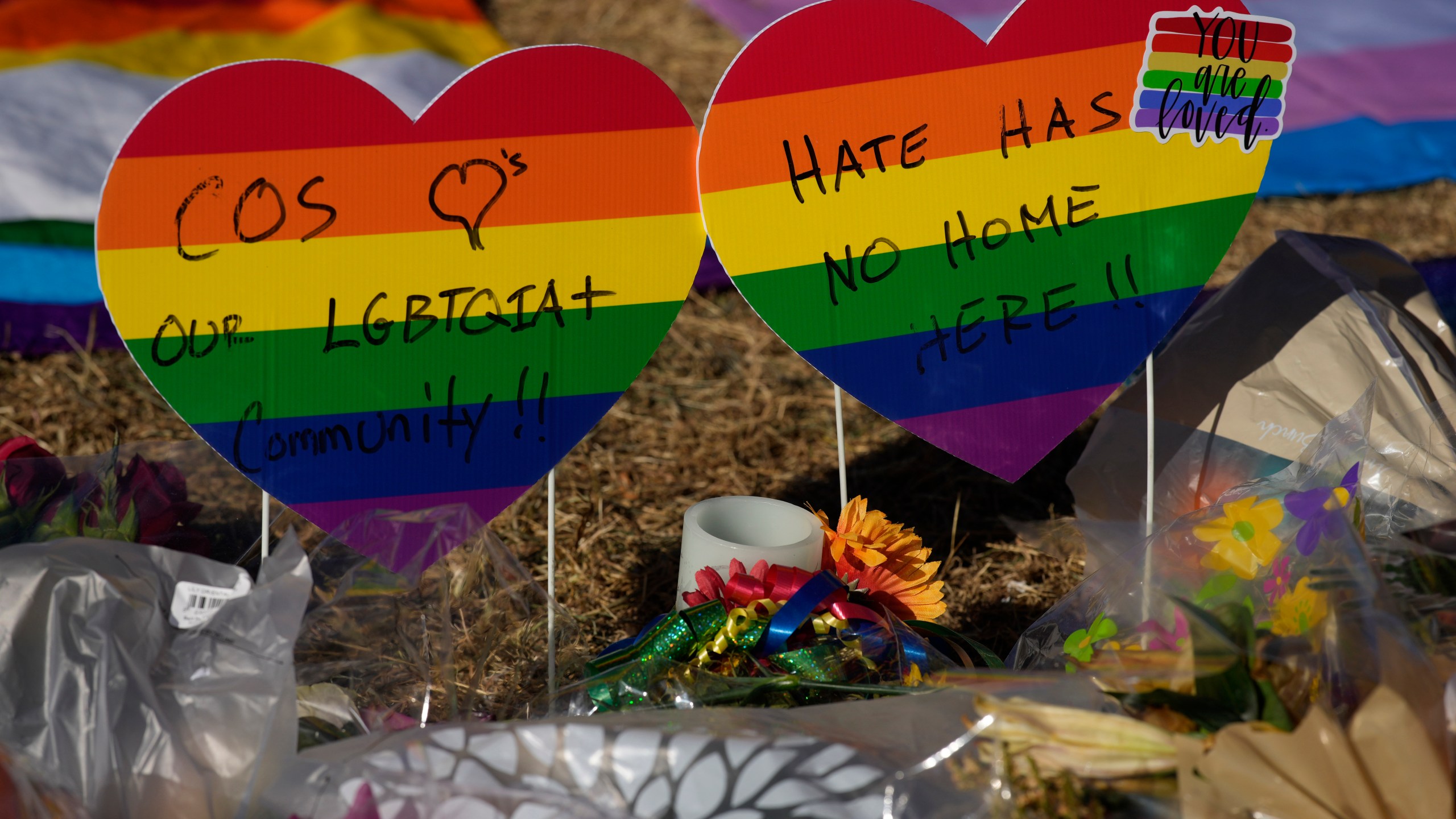 Heart-shaped signs bear messages of support in a makeshift memorial to the victims of a weekend mass shooting at a nearby gay nightclub on Tuesday, Nov. 22, 2022, in Colorado Springs, Colo. Anderson Lee Aldrich opened fire at Club Q, in which five people were killed and others suffered gunshot wounds before patrons tackled and beat the suspect into submission. (AP Photo/David Zalubowski)