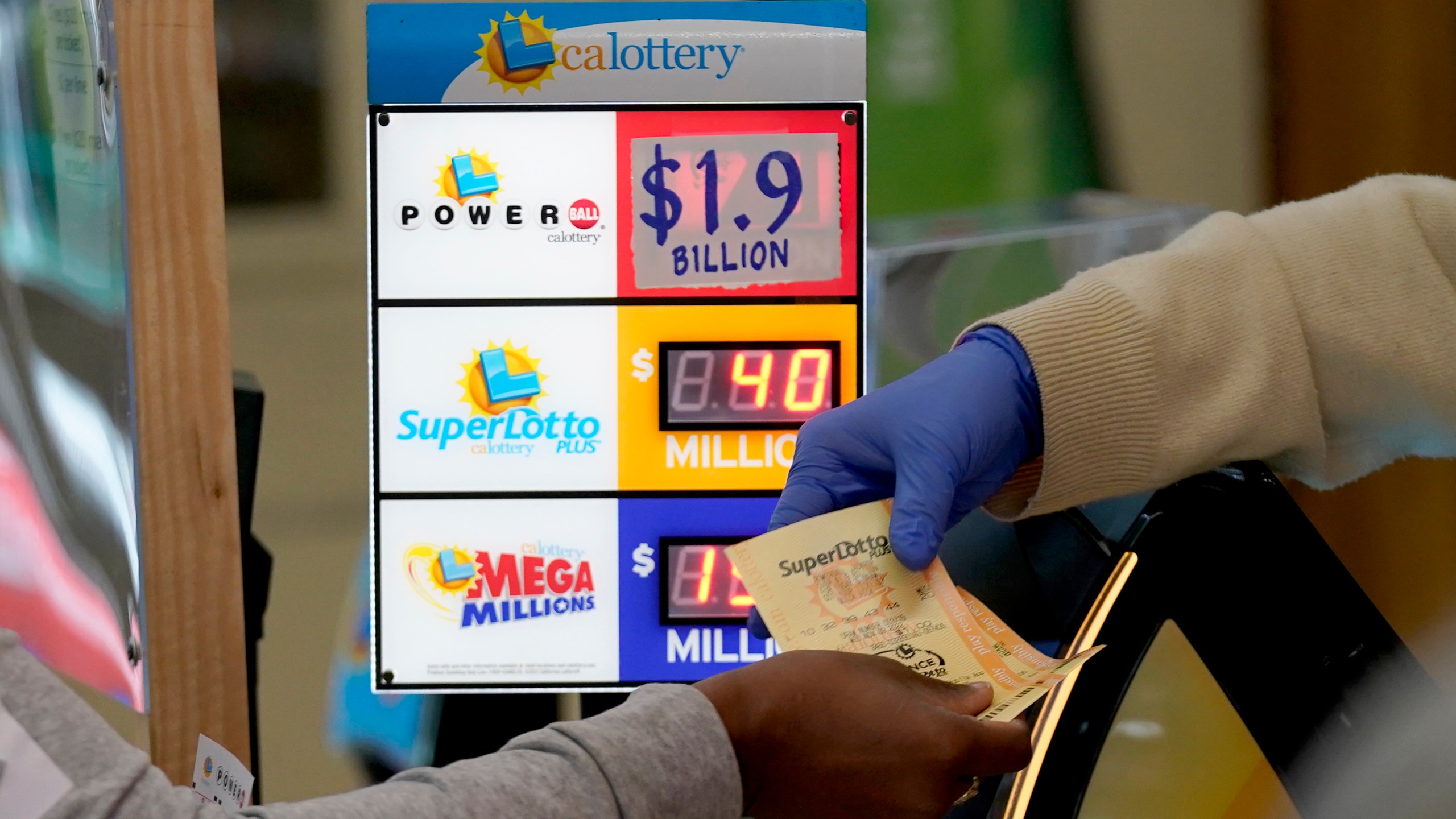 A customer is handed Powerball tickets purchased at Lichine's Liquor & Deli in Sacramento, Calif., Monday, Nov. 7, 2022. Monday night's drawing is estimated to be a record $1.9 billion. (AP Photo/Rich Pedroncelli)