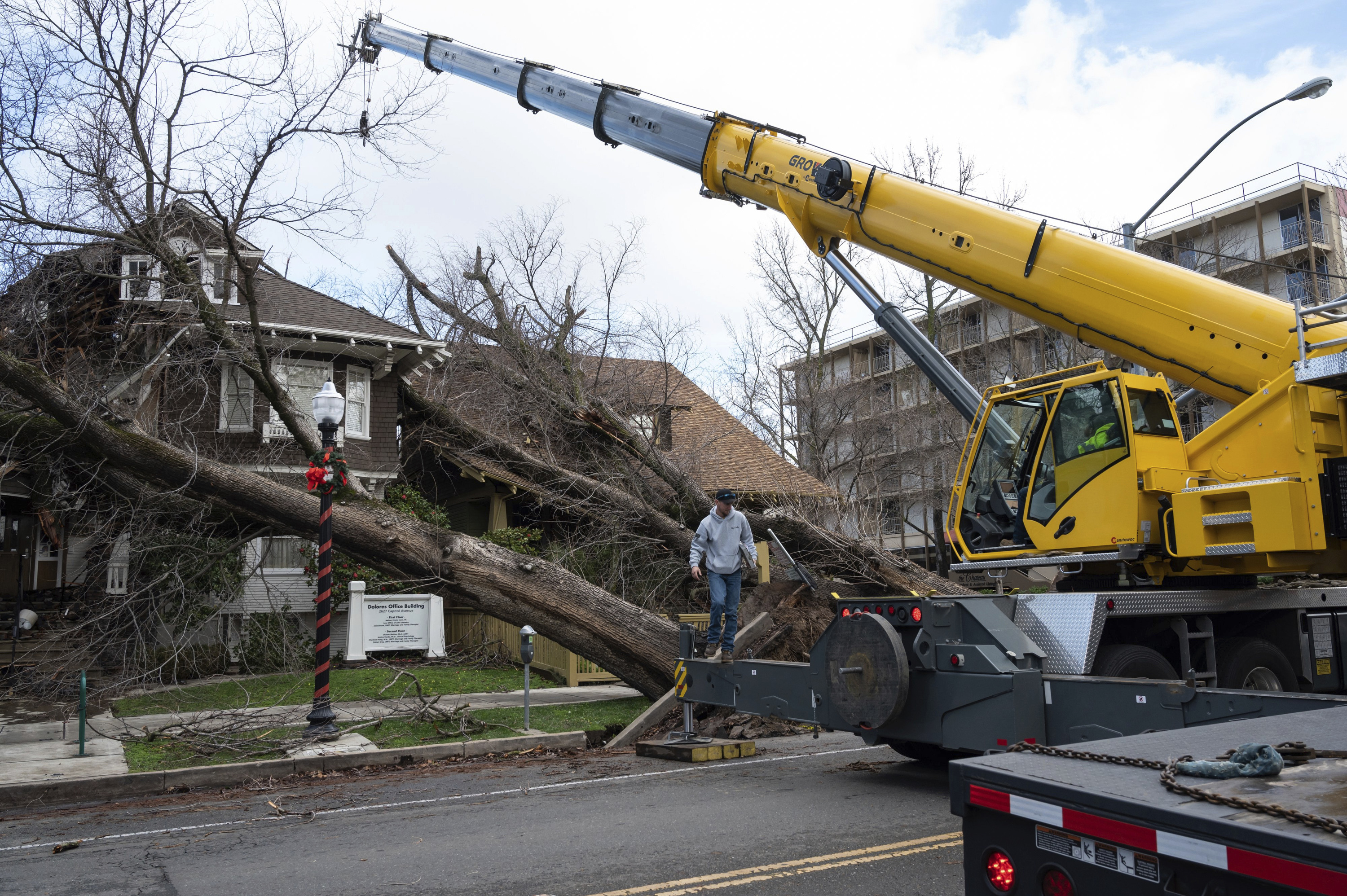 Crane operator Ricky Kapuschinsky, with AAA Crane, gets ready to lift uprooted trees on Capitol Avenue and 27th Street in midtown after a storm brought high winds overnight in Sacramento on Jan. 8, 2023. (Sara Nevis/The Sacramento Bee via AP)