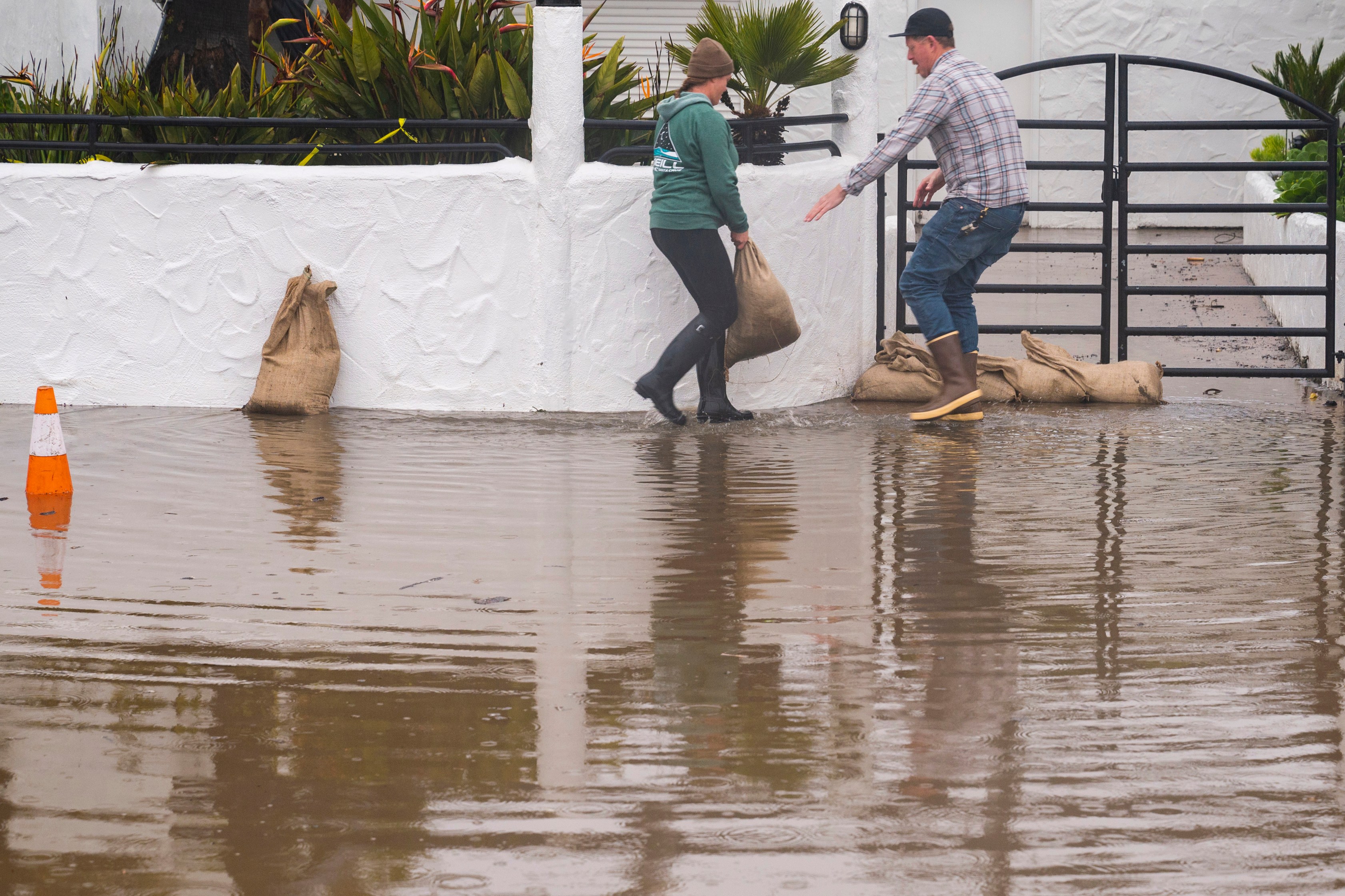 The owners of Venus Pie Trap place sandbags in front of their restaurant in the Rio Del Mar neighborhood of Aptos, Calif., on Jan. 9, 2023. (Nic Coury/Associated Press)