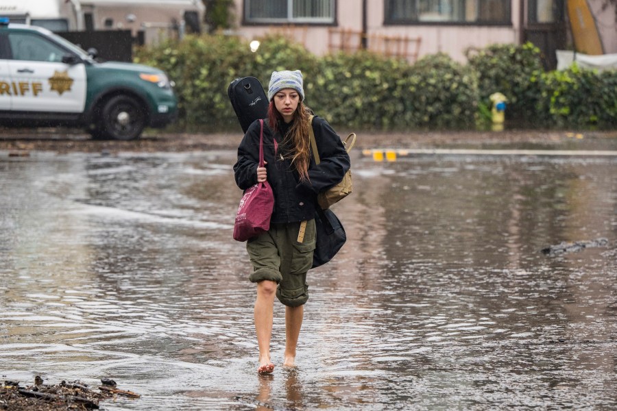 Naia Skogerson evacuates from her house as floodwaters rise in the Rio Del Mar neighborhood of Aptos, Calif., on Jan. 9, 2023. (Nic Coury/Associated Press)