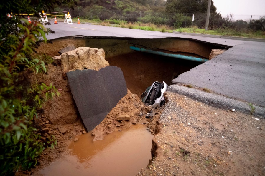 Cars remain in a large sinkhole along Iverson Road in Chatsworth on Jan. 10, 2023. (David Crane/The Orange County Register via AP)