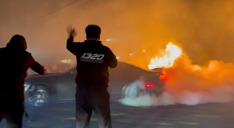 Cars do stunts as Christmas trees burn during a street takeover in Watts on Jan. 9, 2023.