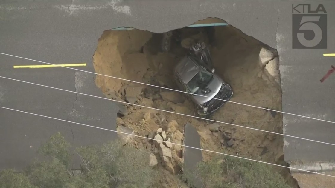 A large sinkhole opened up in the Chatsworth neighborhood of Los Angeles during a torrential downpour, swallowing at least two cars on Jan. 10, 2023 (KTLA)