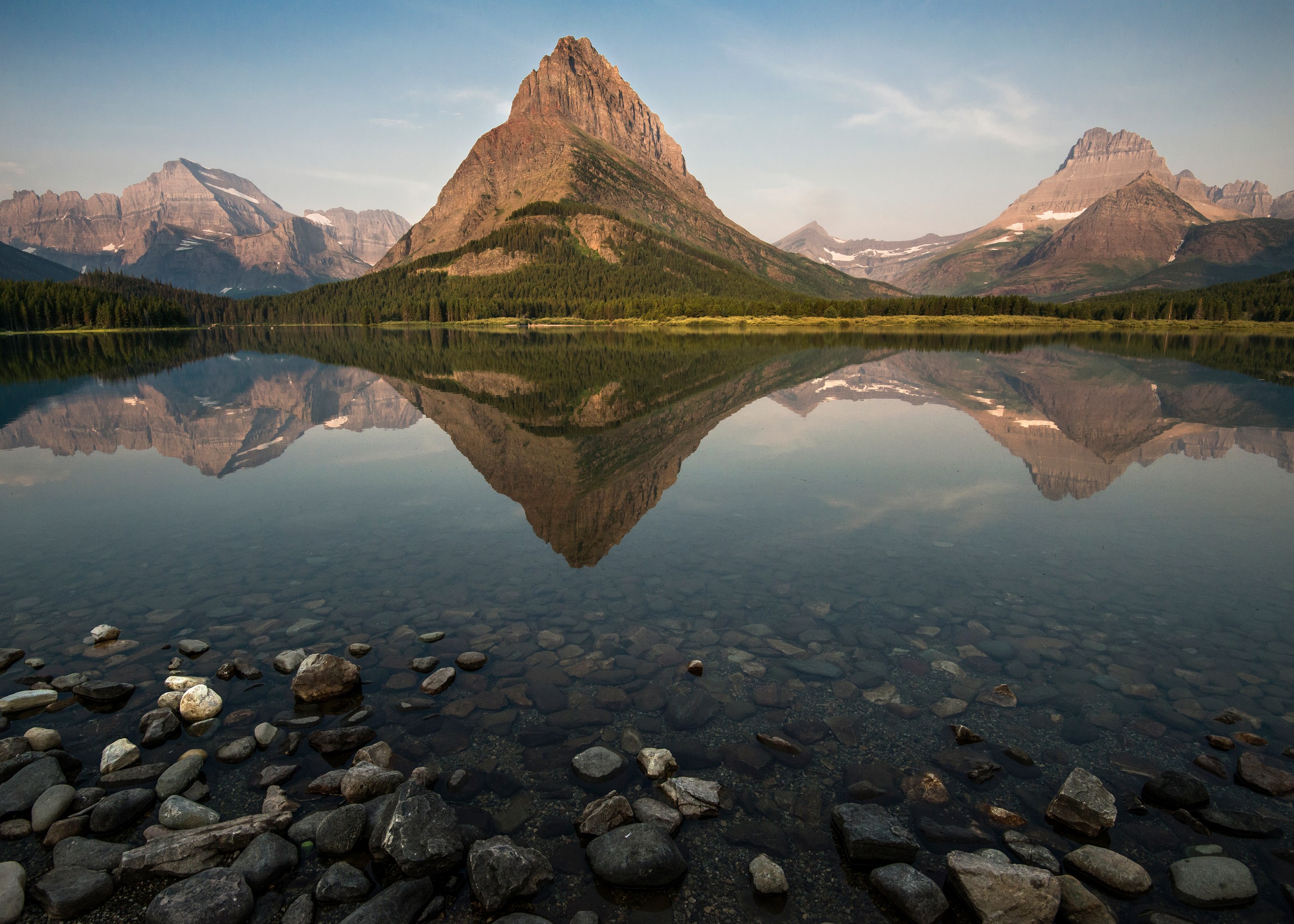 Grinnell Peak is reflected in the still waters of Swiftcurrent Lake at Many Glacier. Mt Gould is to the left and Mt. Wilbur is to the right on May 28, 2014 (Tim Rains/National Park Service)