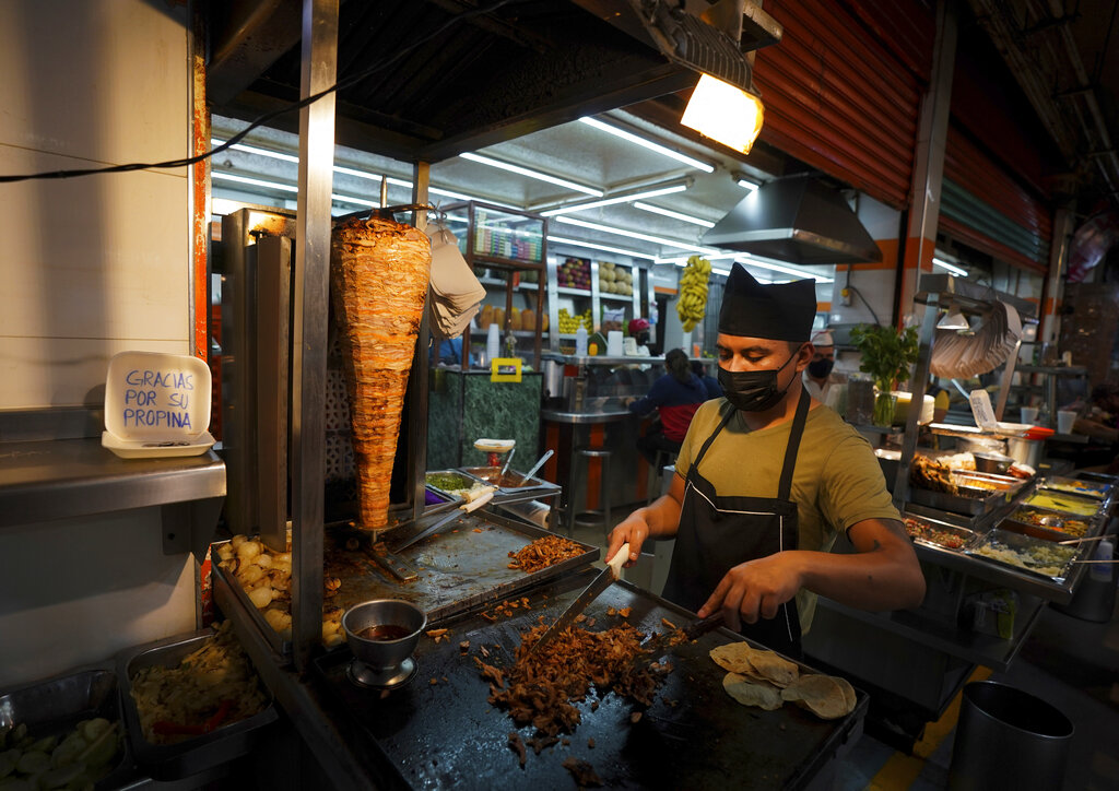 A taco vendor cuts meat