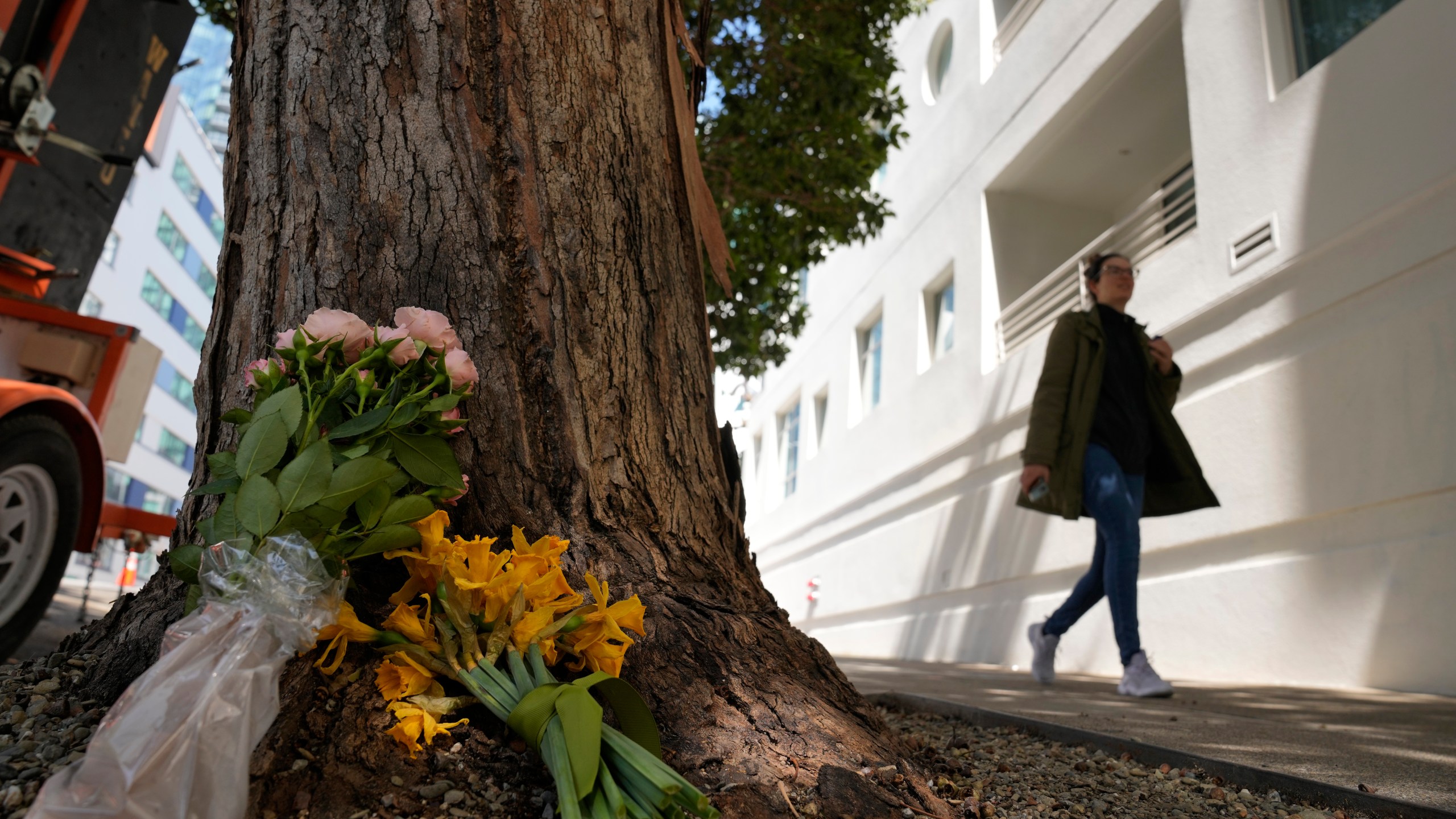 A woman walks past flowers left outside an apartment building where a technology executive was fatally stabbed in San Francisco, Wednesday, April 5, 2023. Bob Lee, a technology executive who created Cash App and was currently chief product officer of MobileCoin, was fatally stabbed in San Francisco early Tuesday, April 4, 2023, according to the cryptocurrency platform and police. (AP Photo/Eric Risberg)