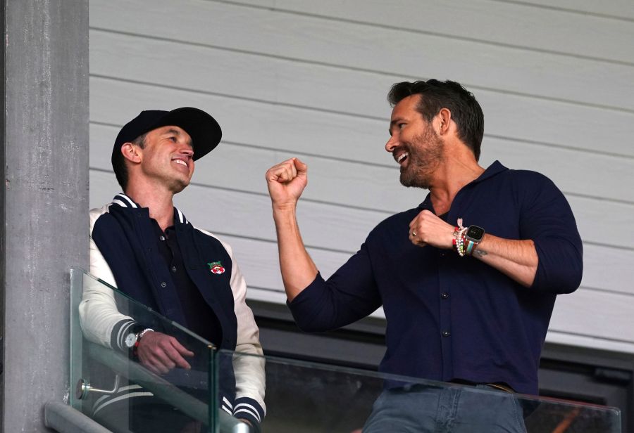 Wrexham co-owners Rob McElhenney, left, and Ryan Reynolds in the stands during the National League soccer match between Wrexham and Boreham Wood at The Racecourse Ground, in Wrexham, Wales, Saturday April 22, 2023. (Martin Rickett/PA via AP)