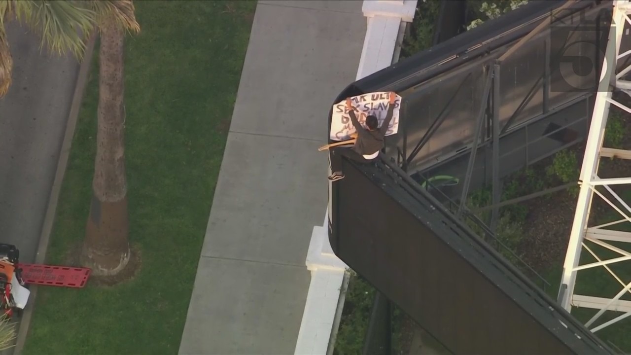 A man was seen climbing the KTLA 5 radio tower in Hollywood while holding a sign that read, “Free Billie Eilish” as authorities worked to remove him on April 25, 2023. (KTLA)