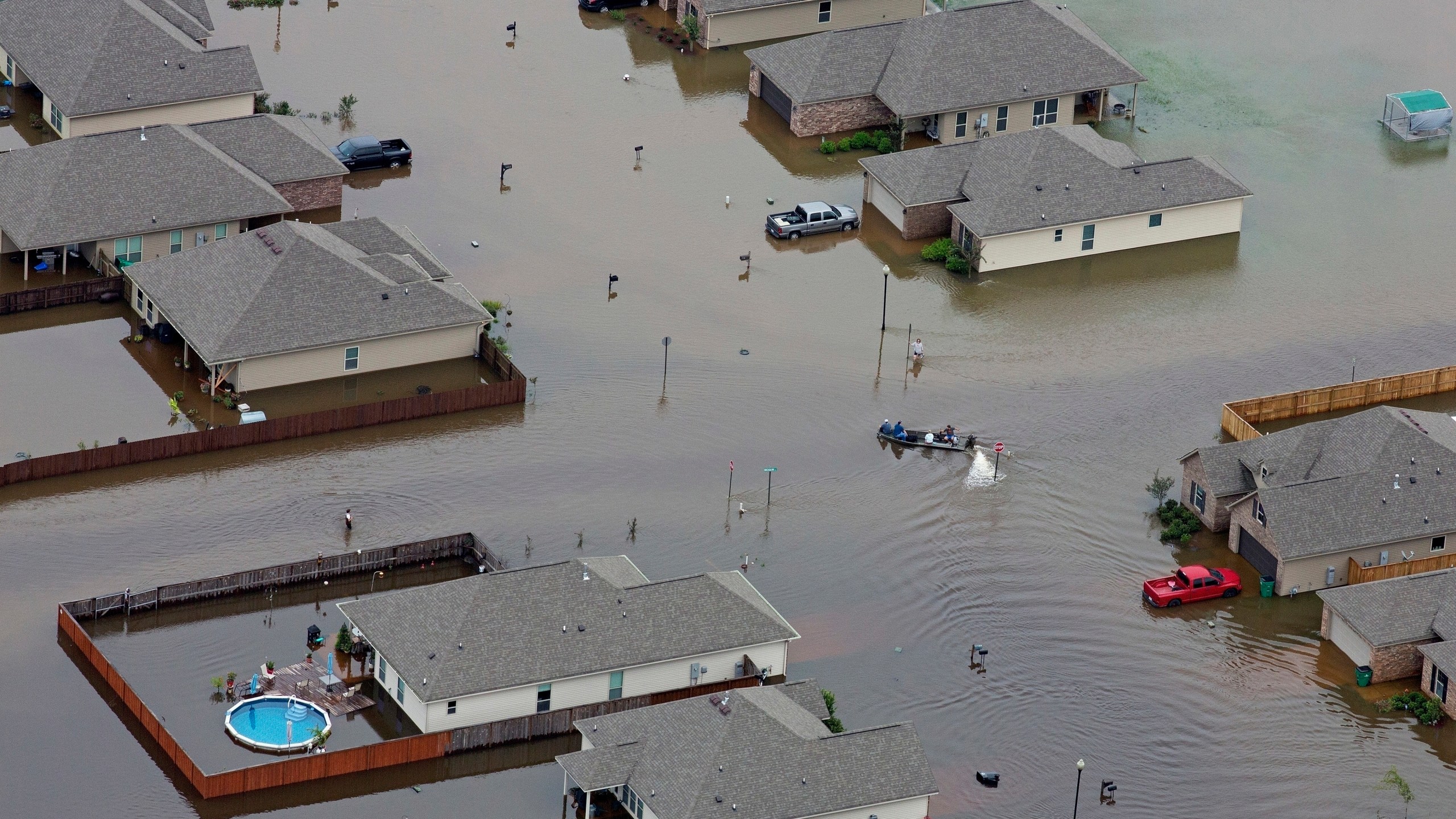 FILE- A boat motors between flooded homes after heavy rains inundating the region, in Hammond, La., on Aug. 13, 2016. A new study Thursday, May 18, 2023, finds the natural burst of El Nino warming that changes weather worldwide is far costlier with longer-lasting expenses than experts had thought, averaging trillions of dollars in damage. (AP Photo/Max Becherer, File)