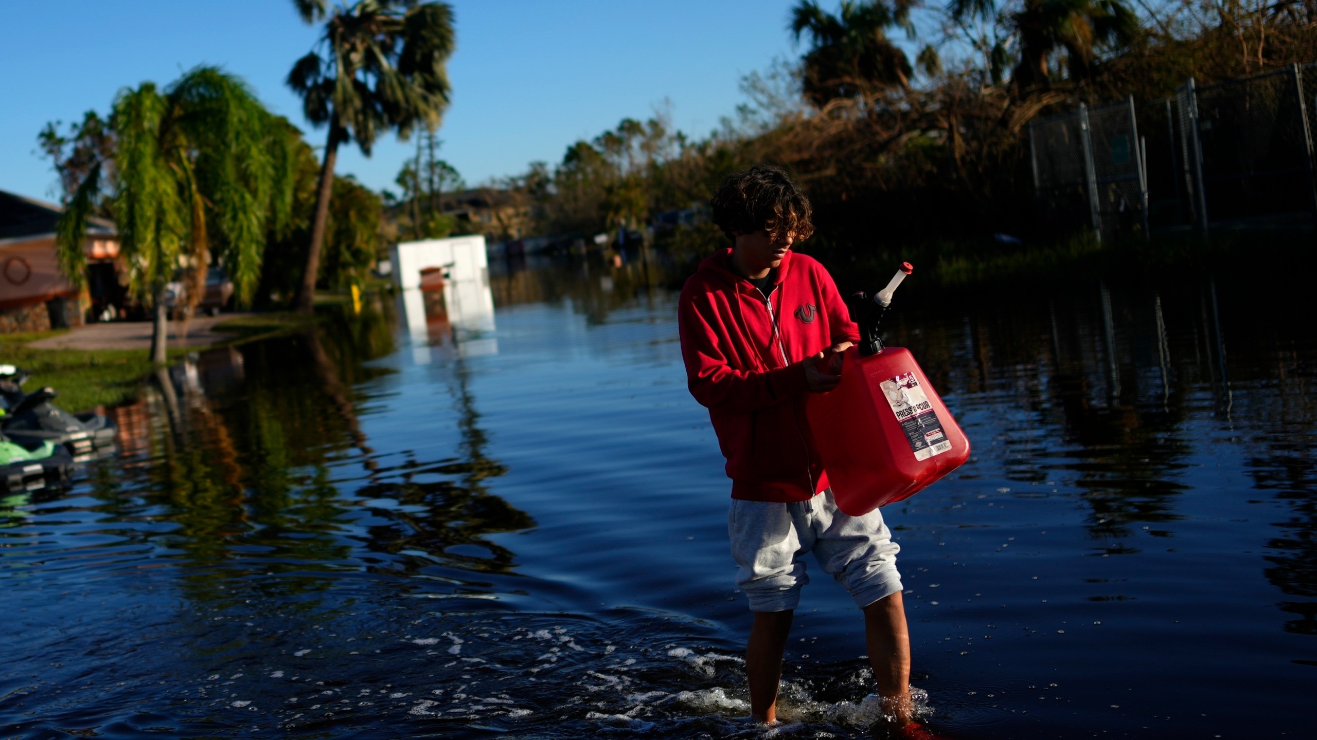 FILE - Jose Cruz, 13, carries an empty Jerrycan through receding flood waters outside his house as his family heads out to look for supplies, three days after the passage of Hurricane Ian, in Fort Myers, Fla., Oct. 1, 2022. After months of gradually warming sea surface temperatures in the tropical Pacific Ocean, NOAA officially issued an El Nino advisory Thursday, June 8, 2023, and stated that this one might be different than the others. (AP Photo/Rebecca Blackwell, File)