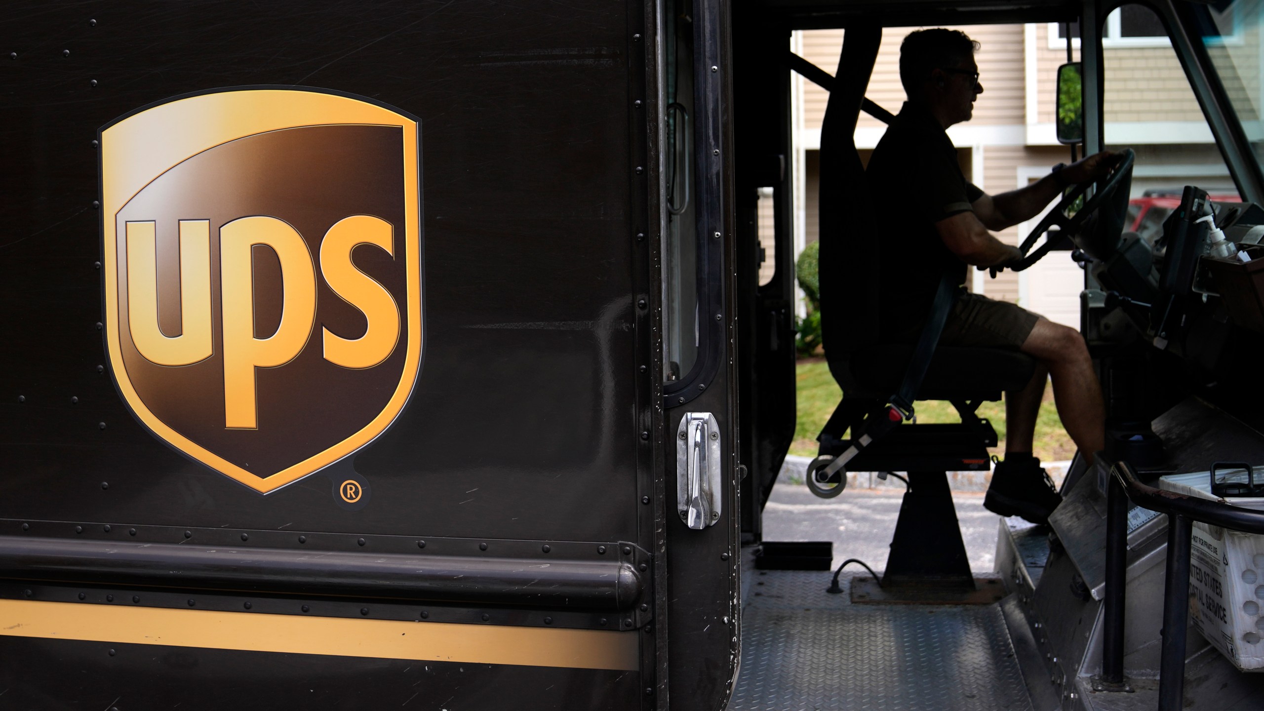 FILE - United Parcel Service driver Hudson de Almeida steers through a neighborhood while delivering packages, June 30, 2023, in Haverhill, Mass. The union representing 340,000 UPS workers said Tuesday, Aug. 22, that its members voted to approve the tentative contract agreement reached last month, putting a final seal on contentious labor negotiations that threatened to disrupt package deliveries for millions of businesses and households nationwide. (AP Photo/Charles Krupa, File)