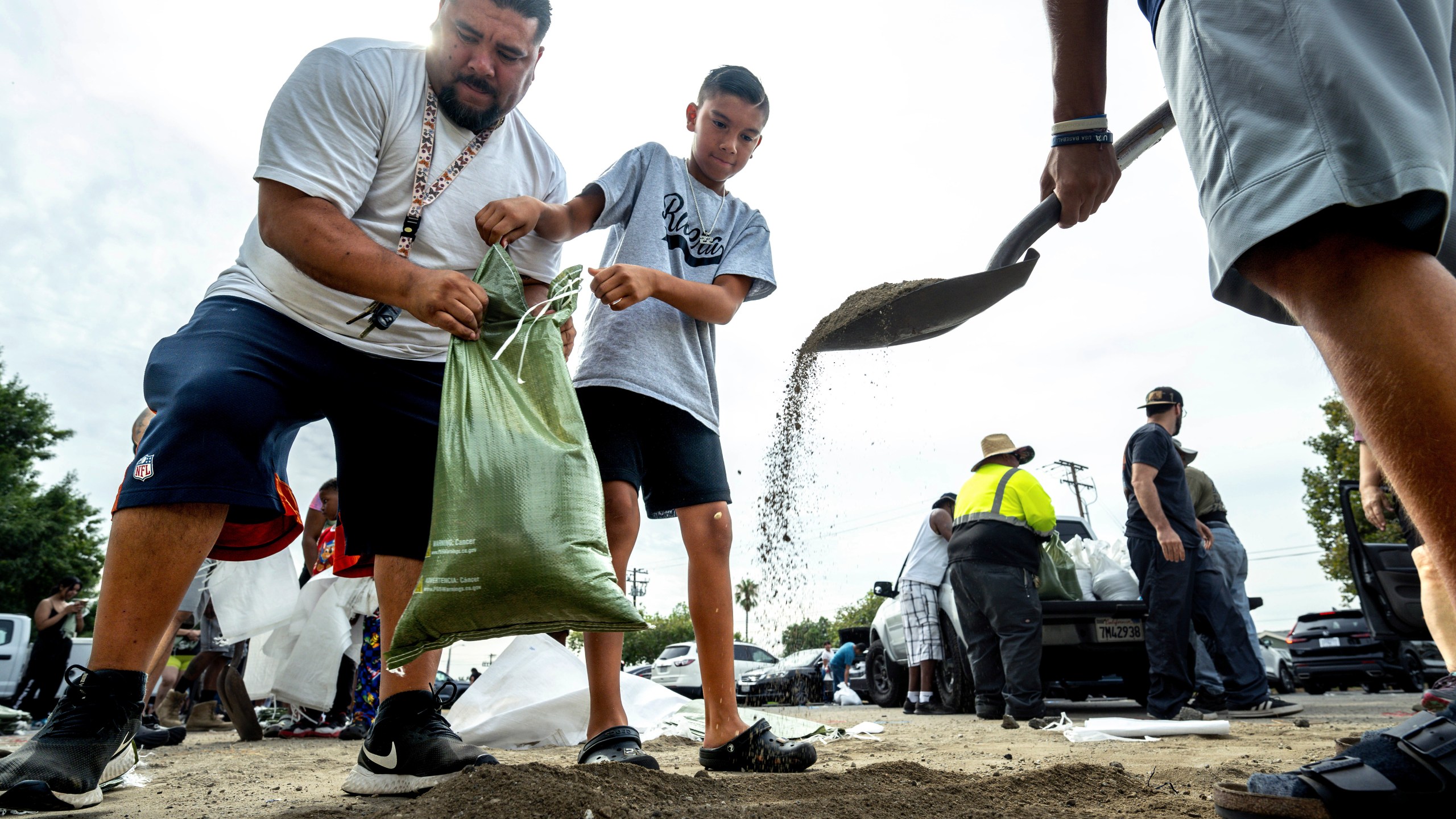 From left; David Rivera makes sandbags with his sons, Zack, 10, center, and Vincent, 18, at Wildwood Park in San Bernardino, Ca., on Saturday, Aug. 19, 2023, as residents gear up for the arrival of Hurricane Hilary. (Watchara Phomicinda/The Orange County Register via AP)