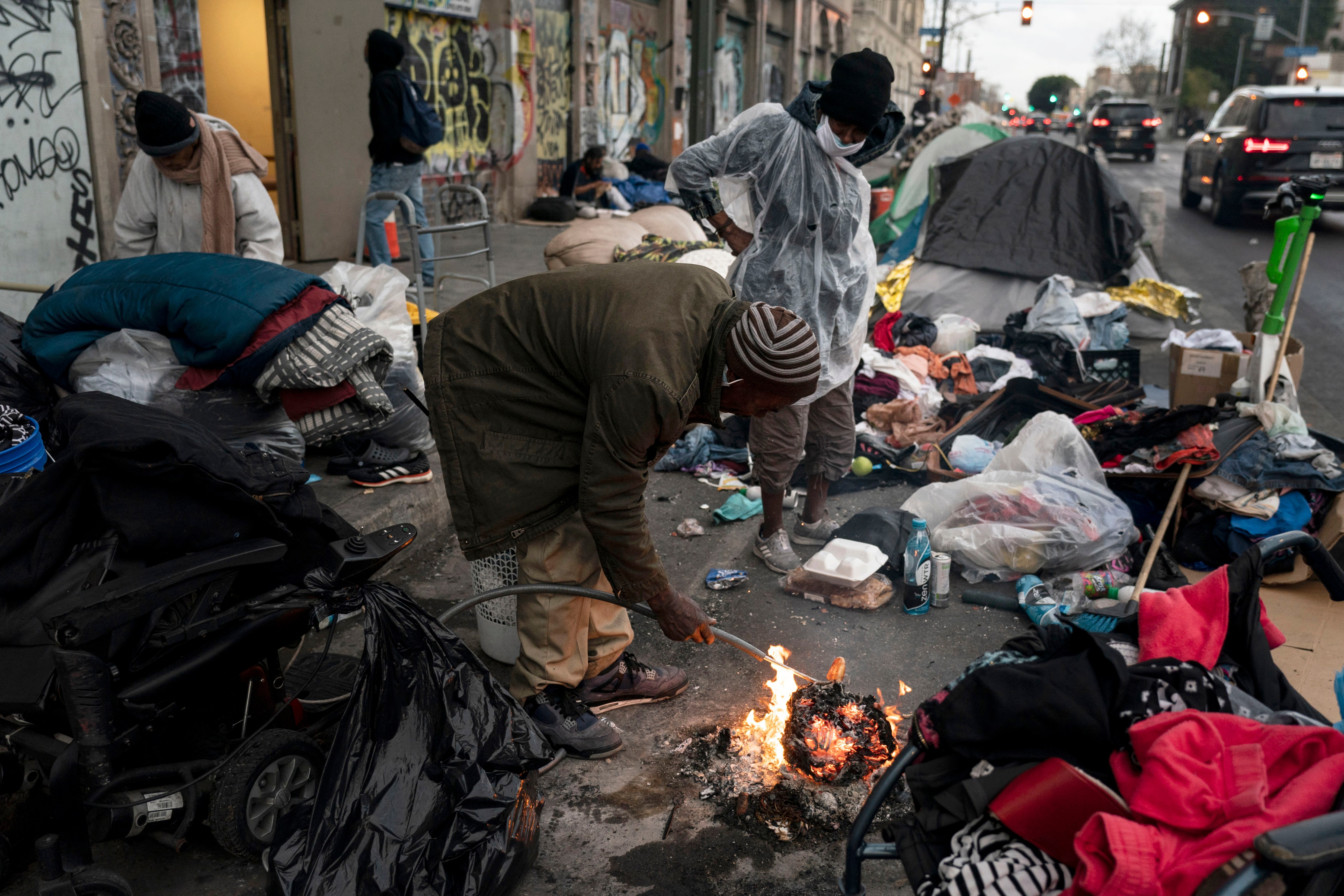 FILE - Robert Mason, a 56-year-old homeless man, warms up a piece of doughnut over a bonfire he set to keep himself warm on Skid Row in Los Angeles, on Feb. 14, 2023. A Sacramento prosecutor is suing California’s capital city over failure to clean up homeless encampments. Sacramento District Attorney Thien Ho announced the suit Tuesday, Sept. 19, 2023, during a news conference in Sacramento. (AP Photo/Jae C. Hong, File)