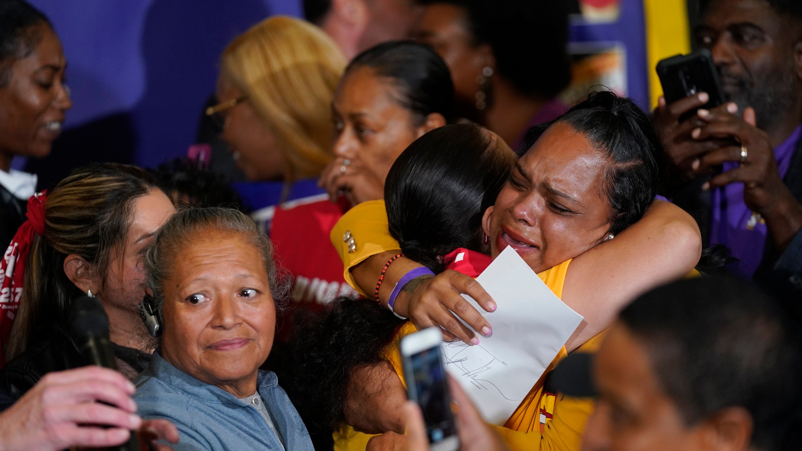 Anneisha Williams, right, who works at a Jack in the Box restaurant in Southern California celebrates as she holds the bill signed by California Gov. Gavin Newsom at the SEIU Local 721 in Los Angeles, Thursday, Sept. 28, 2023. California fast food workers will be paid at least $20 per hour next year under the new law signed by Newsom. (AP Photo/Damian Dovarganes)