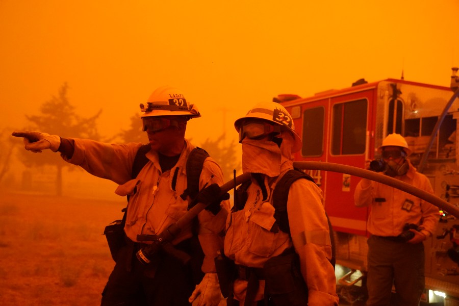 Robert Ortiz, left, and Alexis Miller of Los Angeles County Fire talk about a plan of attach while protecting a home from the advancing Bobcat Fire along Cima Mesa Rd. Friday, Sept. 18, 2020, in Juniper Hills, Calif. (AP Photo/Marcio Jose Sanchez)