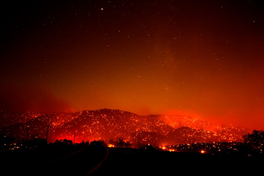 Flames from the Bobcat Fire dot a hill under a glowing smoky sky in Juniper Hills, Calif., Friday, Sept. 18, 2020. (AP Photo/Ringo H.W. Chiu)