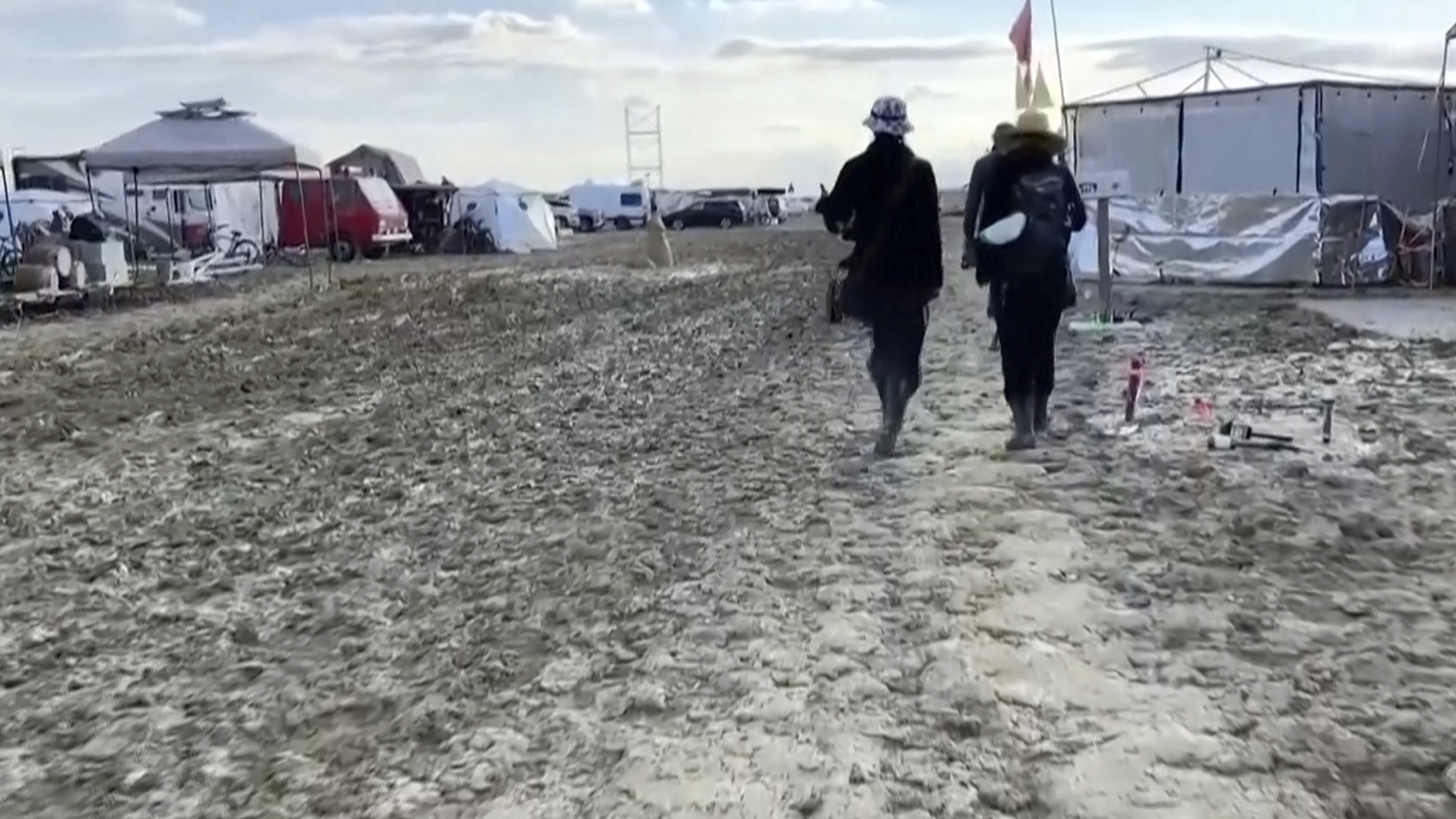 In this image from video provided by Rebecca Barger, people walk along a muddy path at the Burning Man festival site in Black Rock, Nev., on Sept. 4, 2023. (Rebecca Barger/@rebeccabargerphoto via AP)