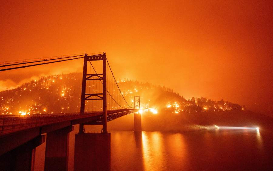 A boat motors by as the Bidwell Bar Bridge is surrounded by fire in Lake Oroville during the Bear fire in Oroville, California on September 9, 2020. (Getty Images)