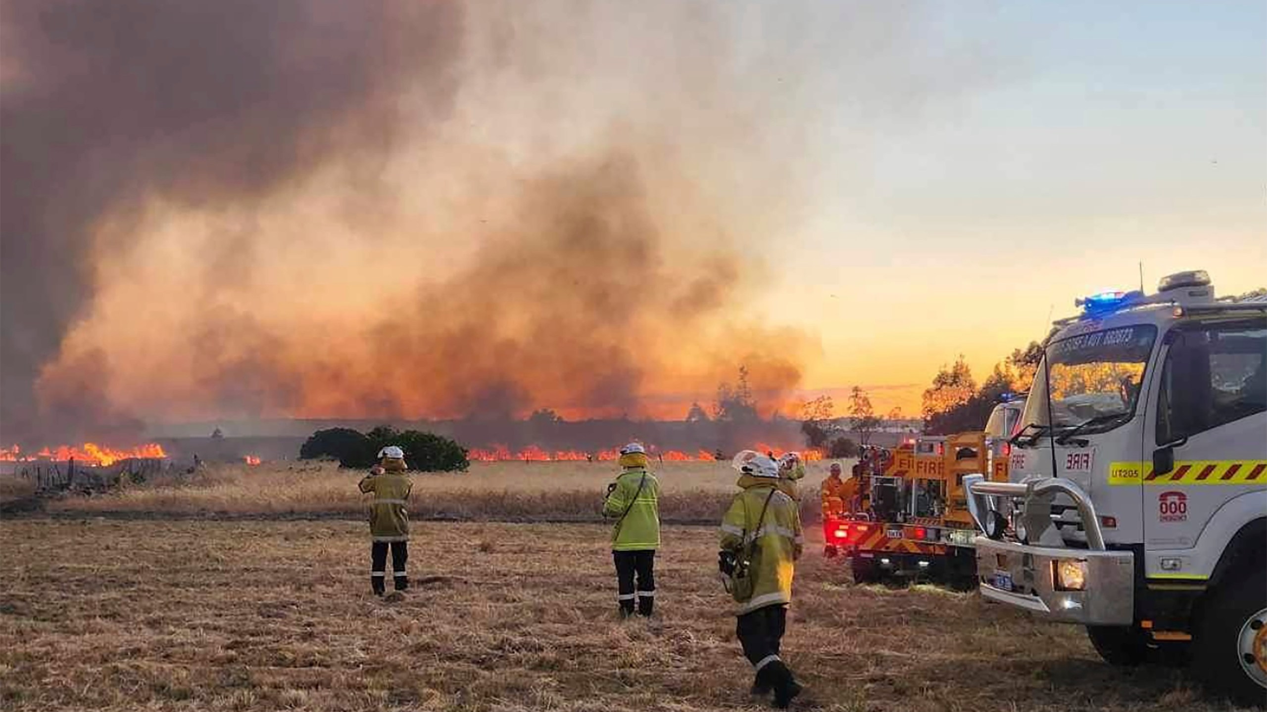 West Australian firefighters watch as grassland burns near the West Australian city of Wannaroo, north of Perth in the early hours of Thursday, Nov. 23, 2023. Dozens of residents have been evacuated and at least 10 homes have been destroyed by a wildfire that is burning out of control on the northern fringe of the west coast city of Perth during heatwave spring conditions, authorities say.(DFES via AP)