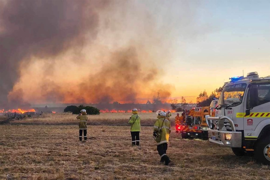 West Australian firefighters watch as grassland burns near the West Australian city of Wannaroo, north of Perth in the early hours of Thursday, Nov. 23, 2023. Dozens of residents have been evacuated and at least 10 homes have been destroyed by a wildfire that is burning out of control on the northern fringe of the west coast city of Perth during heatwave spring conditions, authorities say.(DFES via AP)