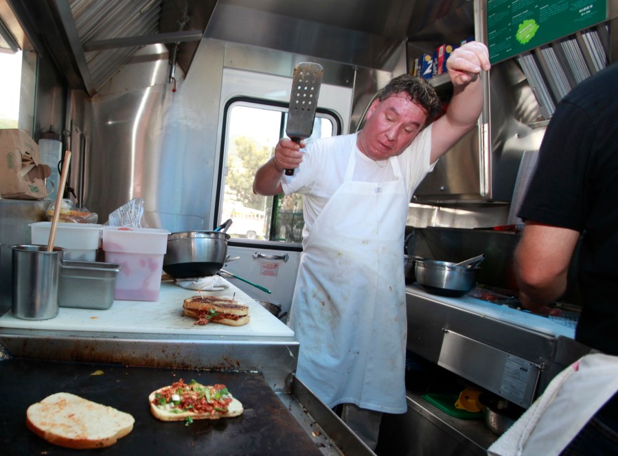 This Sept. 28, 2010 file photo shows Greenz on Wheelz food truck chef Javier Mendez reacting to the heat as he grills a sandwich in Los Angeles. (AP Photo/Damian Dovarganes, File)