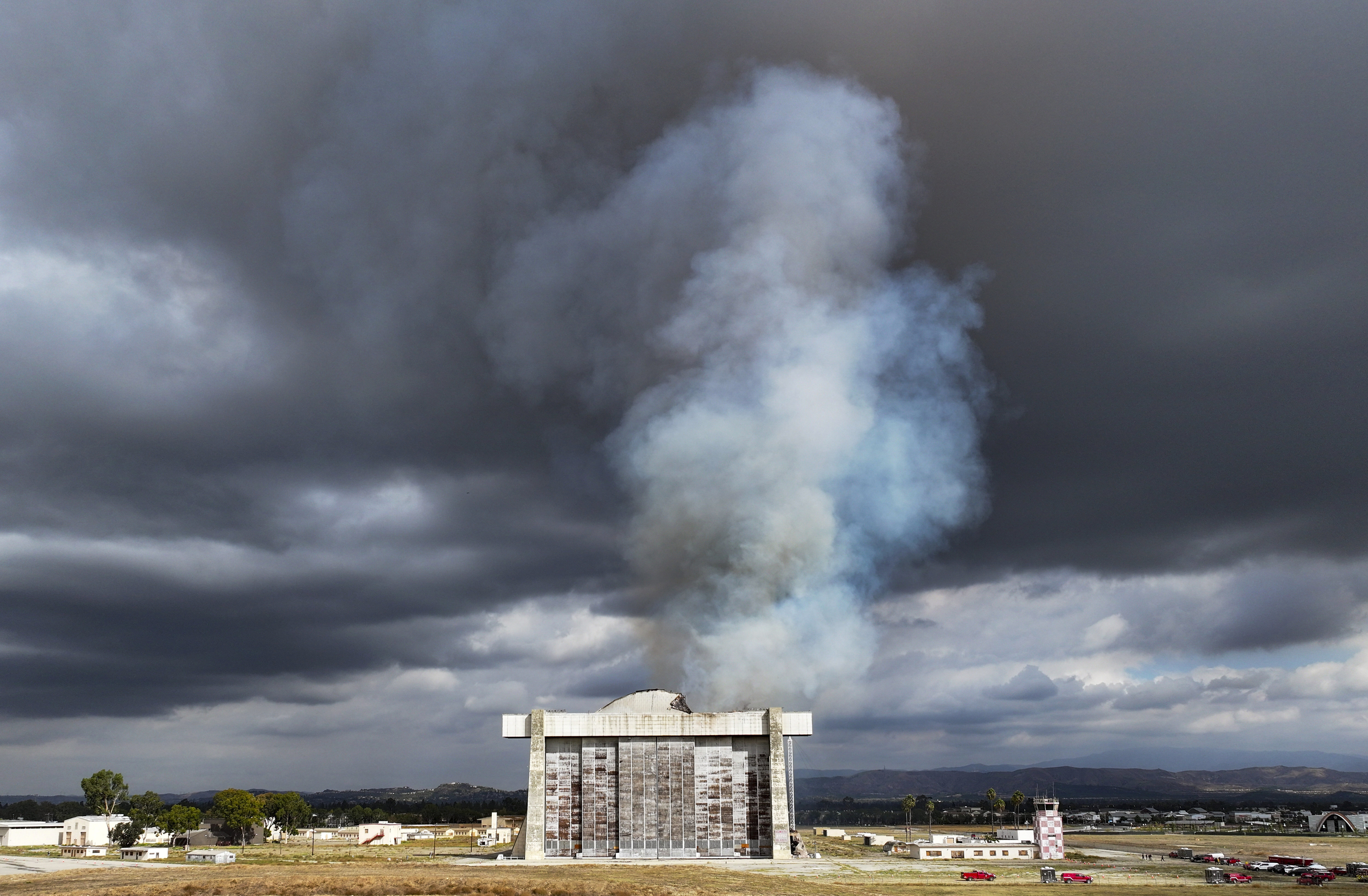 Firefighters work to control a blaze at the north blimp hangar at the former Marine Corps Air Station Tustin in Tustin, Calif., on Tuesday, Nov. 7, 2023. Fire raged Tuesday in a massive World War II-era wooden hangar that was built to house military blimps based in Southern California. (Jeff Gritchen/The Orange County Register via AP)