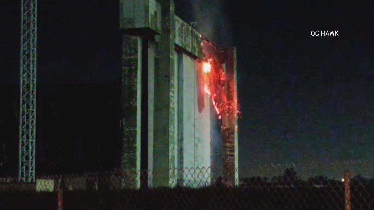 An active flare-up of a fire seen on the doors of a historic airbase hangar in Tustin on Nov. 11 has prompted concerns from residents. (OC Hawk)