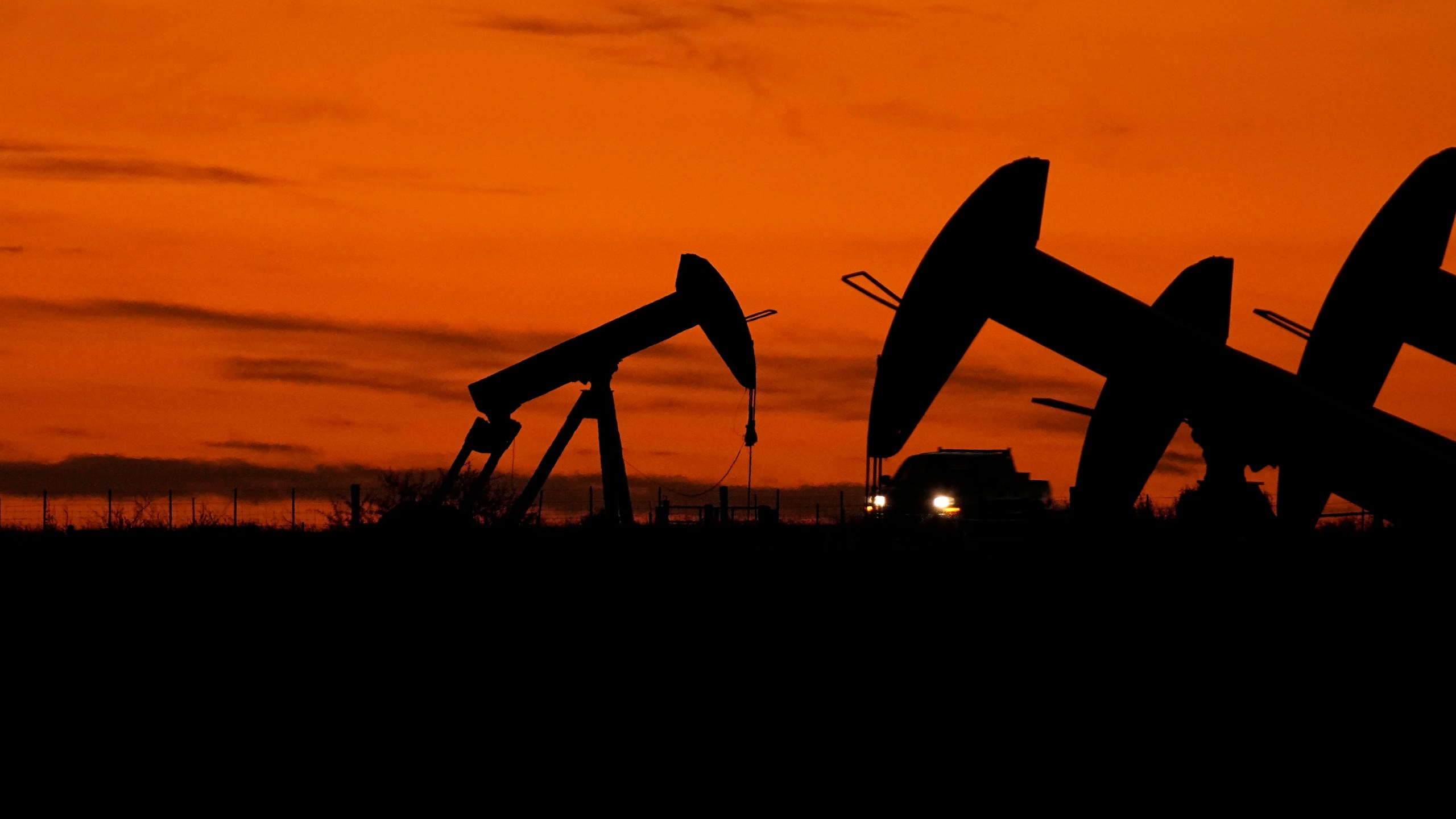 File - A truck passes oil pump jacks at dusk near Karnes City, Texas, Nov. 1, 2023. On Wednesday, the Labor Department releases producer prices data for November. The producer price index is an indicator measuring inflation at the wholesale level, hitting businesses before they pass costs along to consumers. (AP Photo/Eric Gay, File)